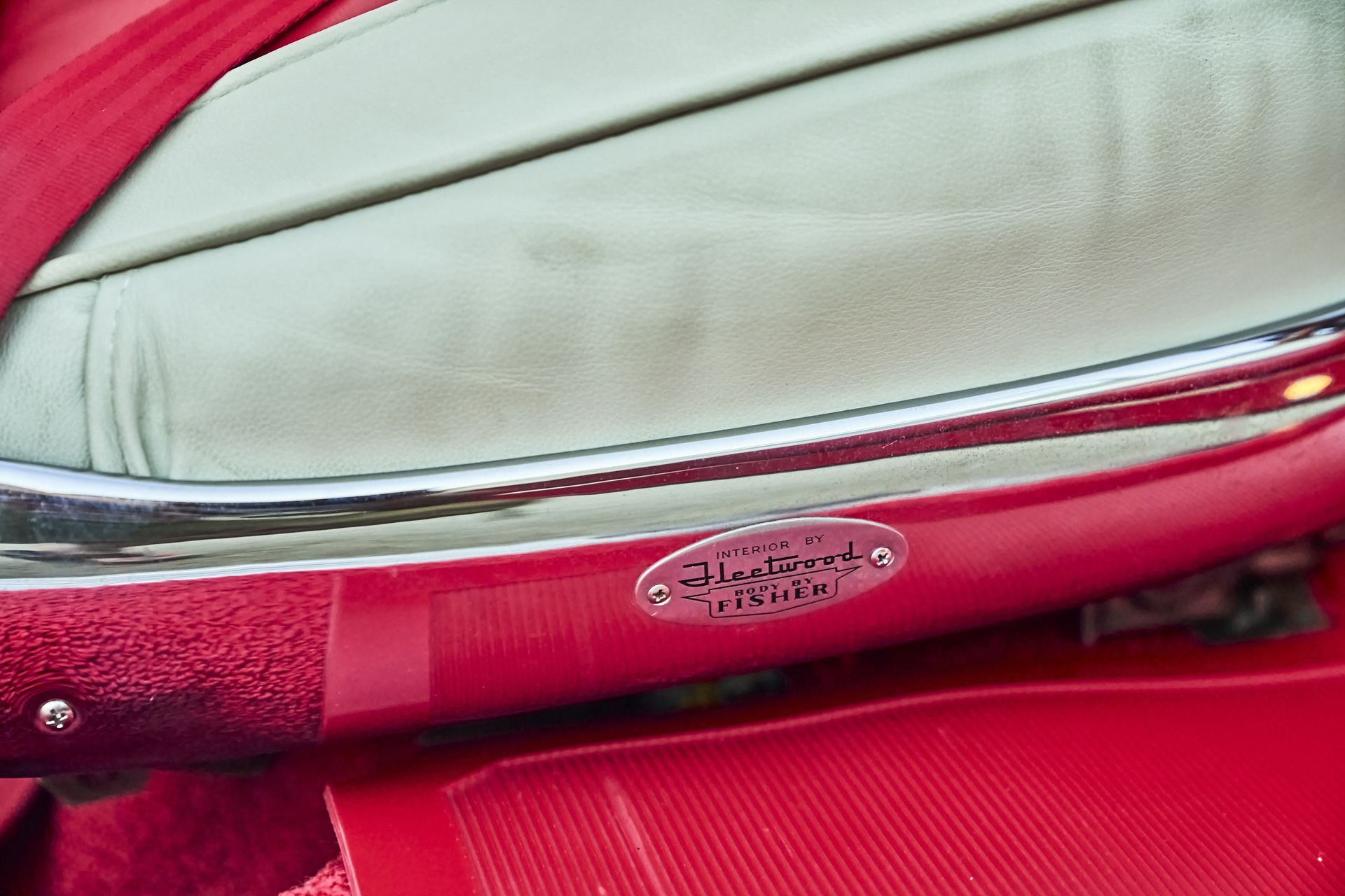A close up of a red car with a white seat and a chrome trim.