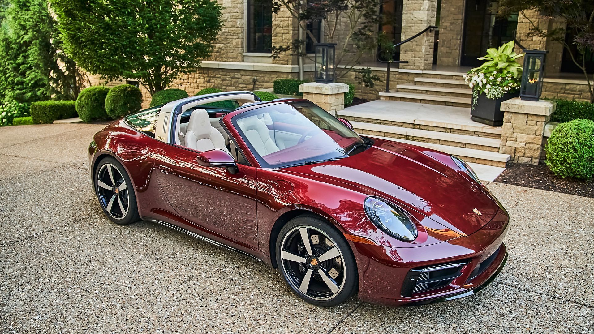 A red porsche targa is parked in front of a house.