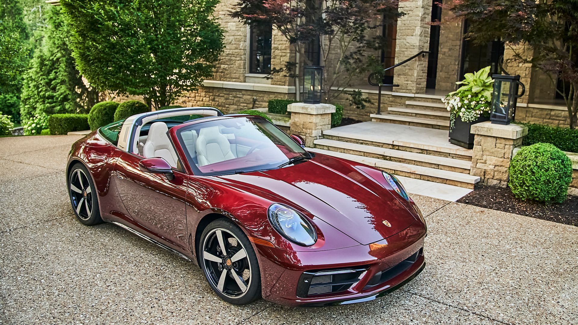 A red porsche targa is parked in front of a house.
