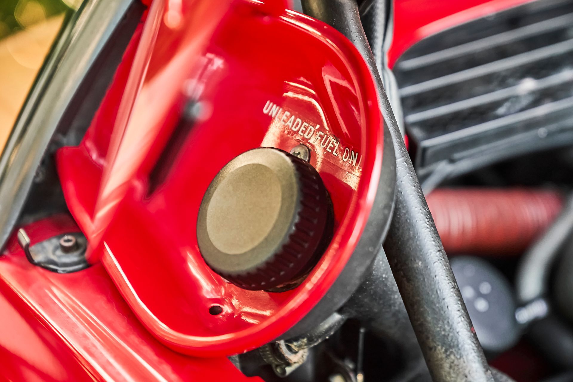 A close up of a red motorcycle with a black knob