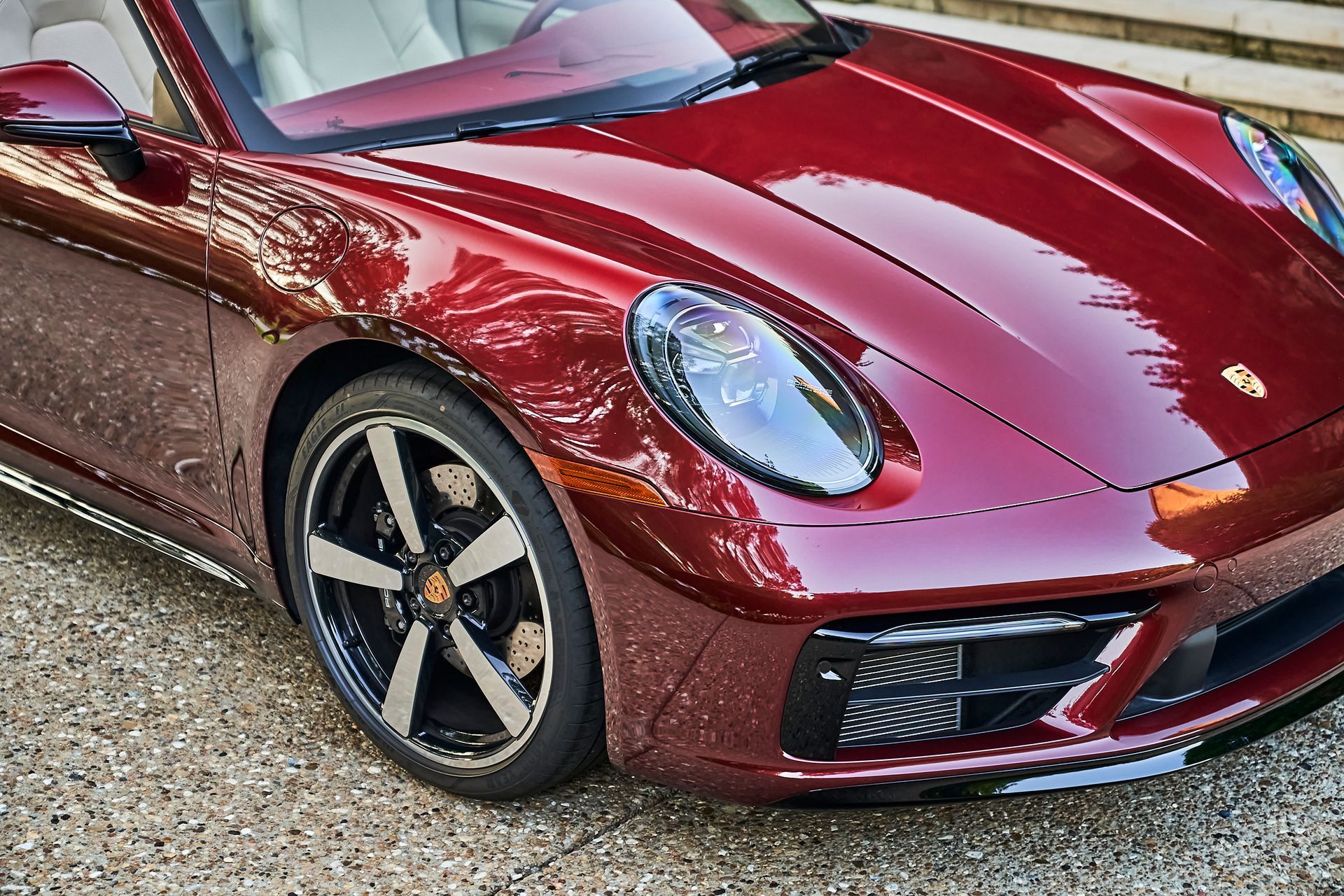 A red porsche 911 is parked on a gravel road