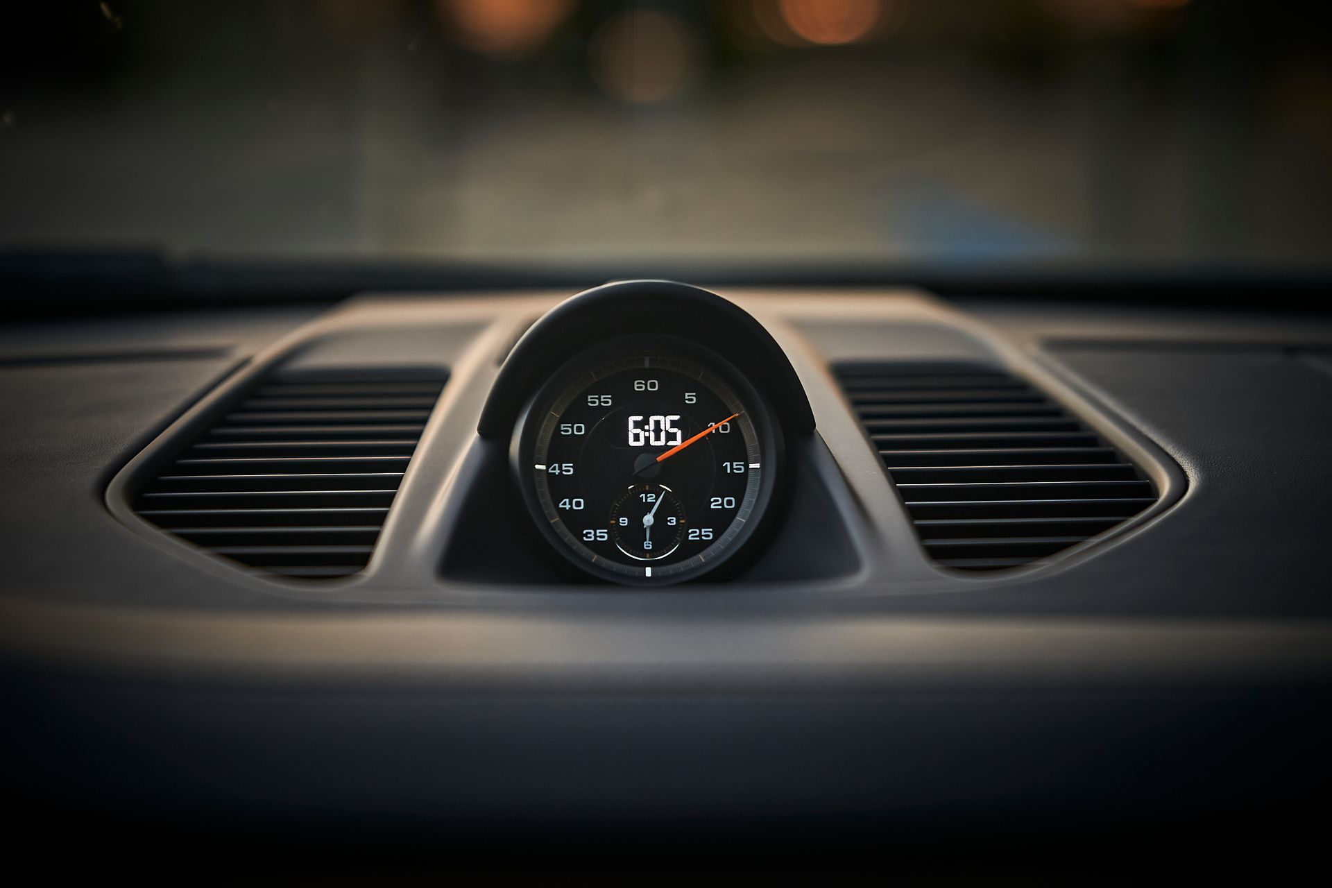 A clock on the dashboard of a car reads 6:05