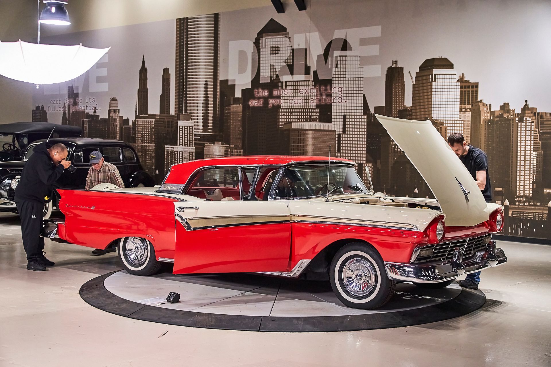 A red and white car with the hood up in a garage