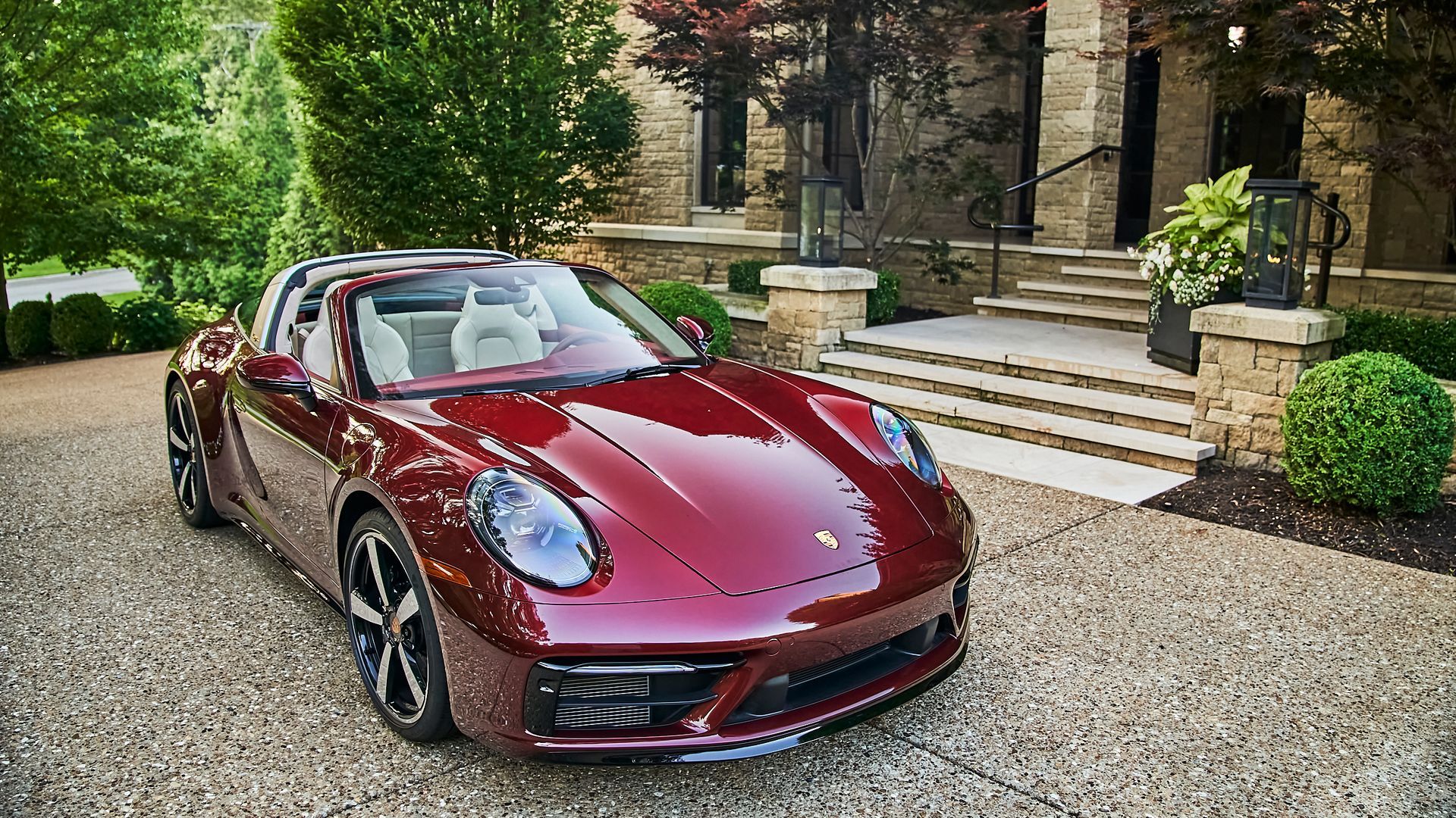 A red porsche targa is parked in front of a house.