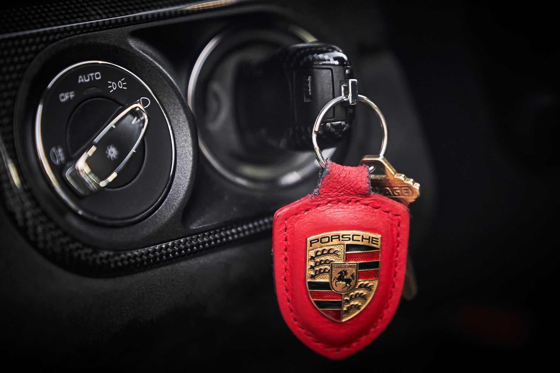 A red porsche keychain is in the ignition of a car