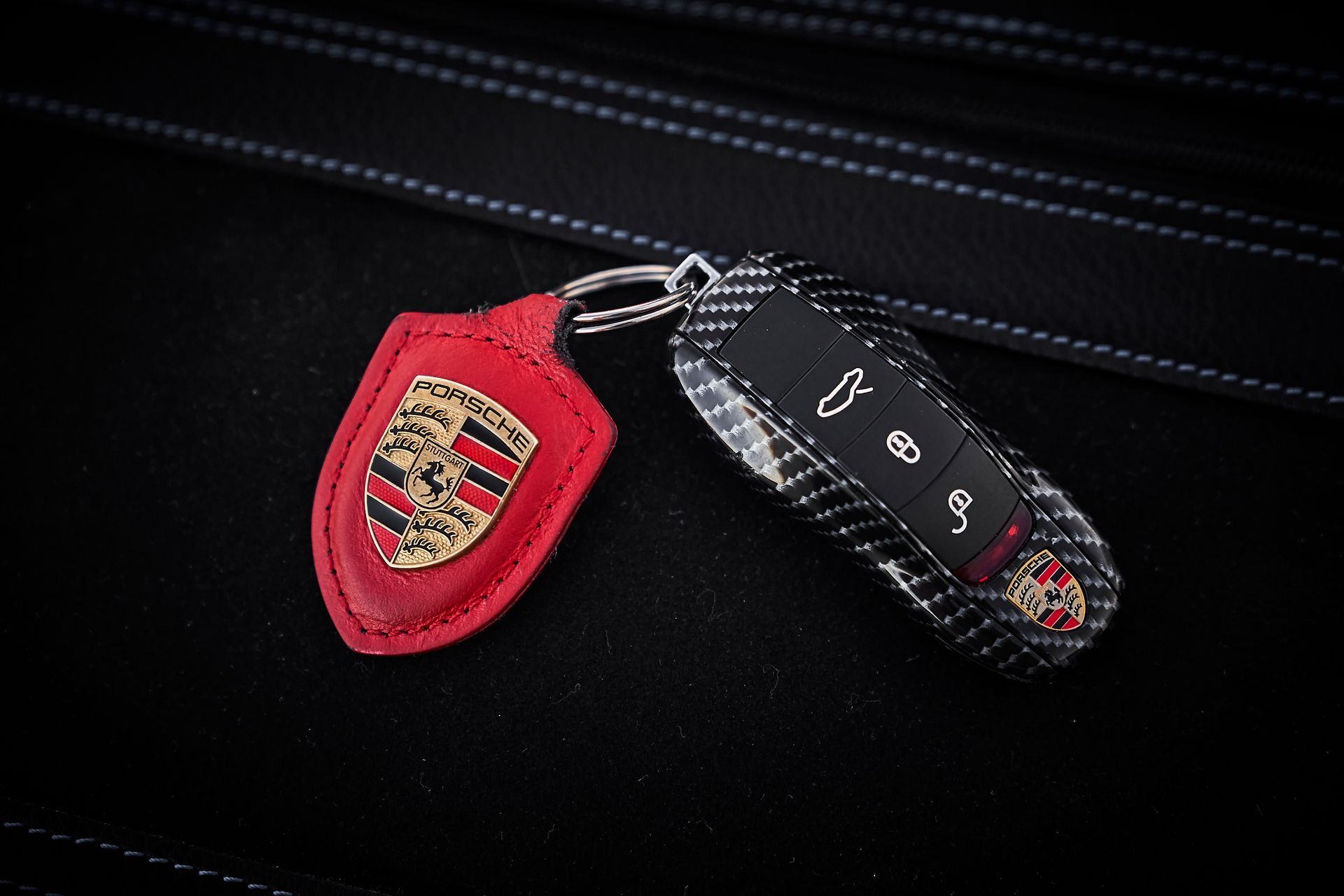A car key with a porsche logo on it is sitting on a black leather seat.