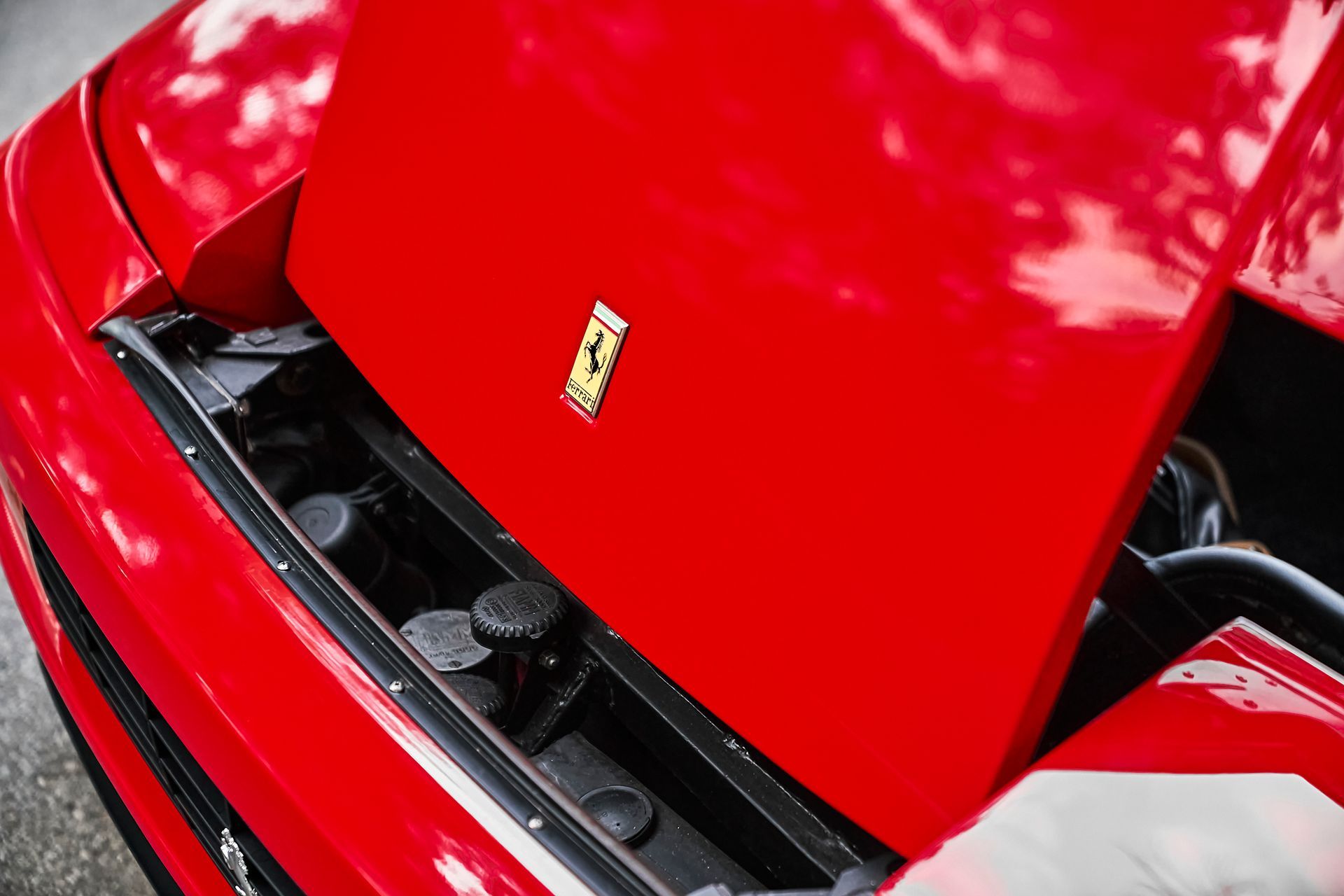 The hood of a red ferrari with the hood open.