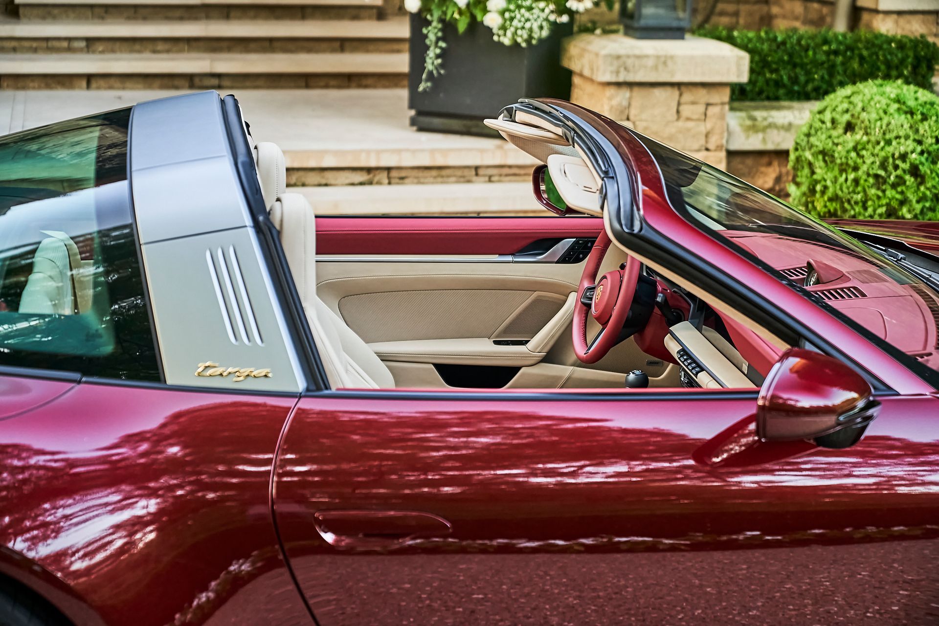 A red sports car with the top down is parked in front of a house.