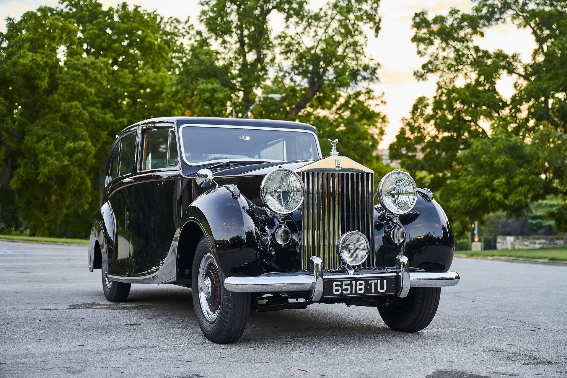 A black rolls royce limousine is parked in a parking lot.