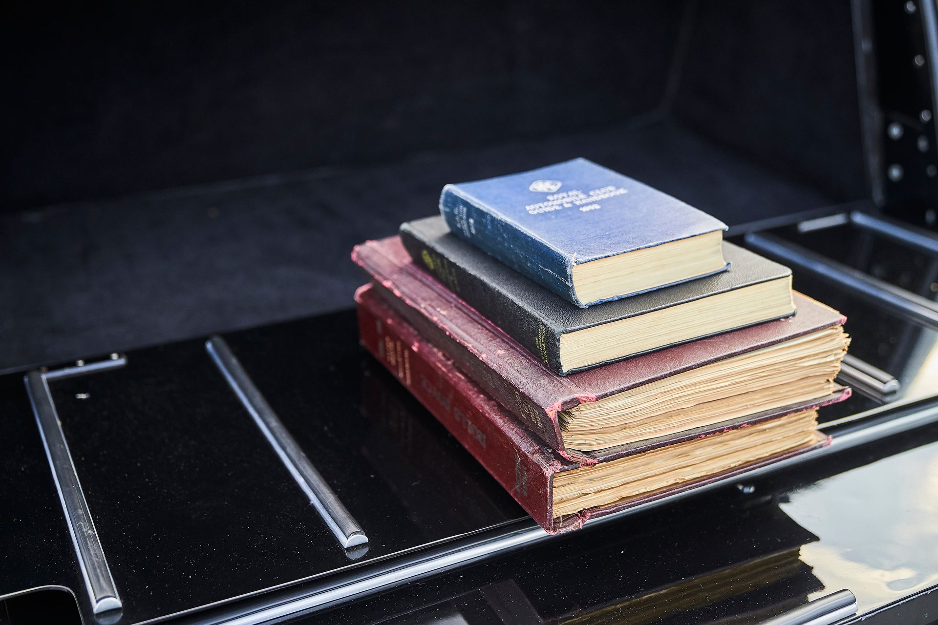 A stack of books is sitting on the back of a car.