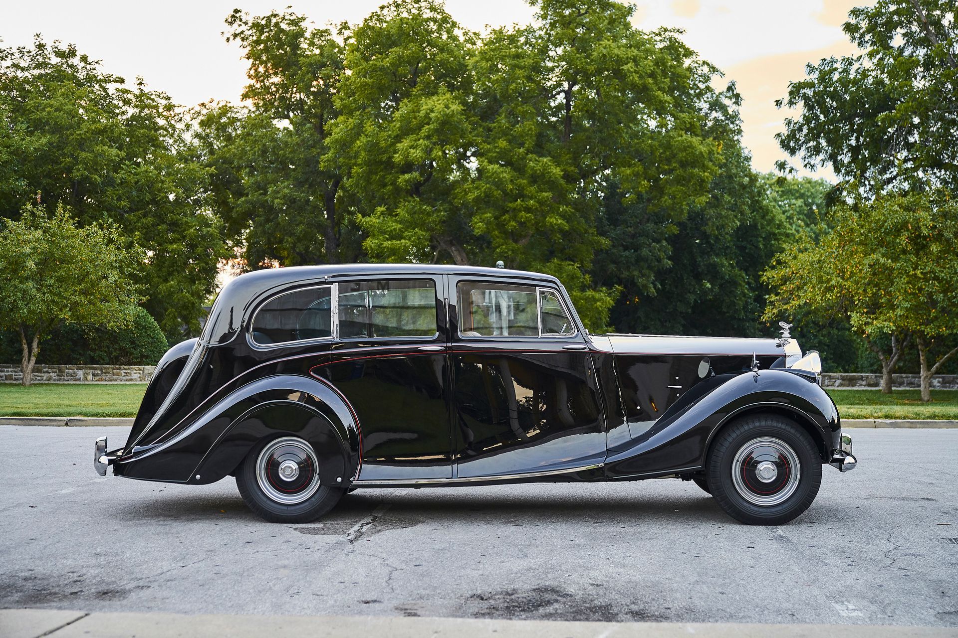 An old black car is parked on the side of the road.