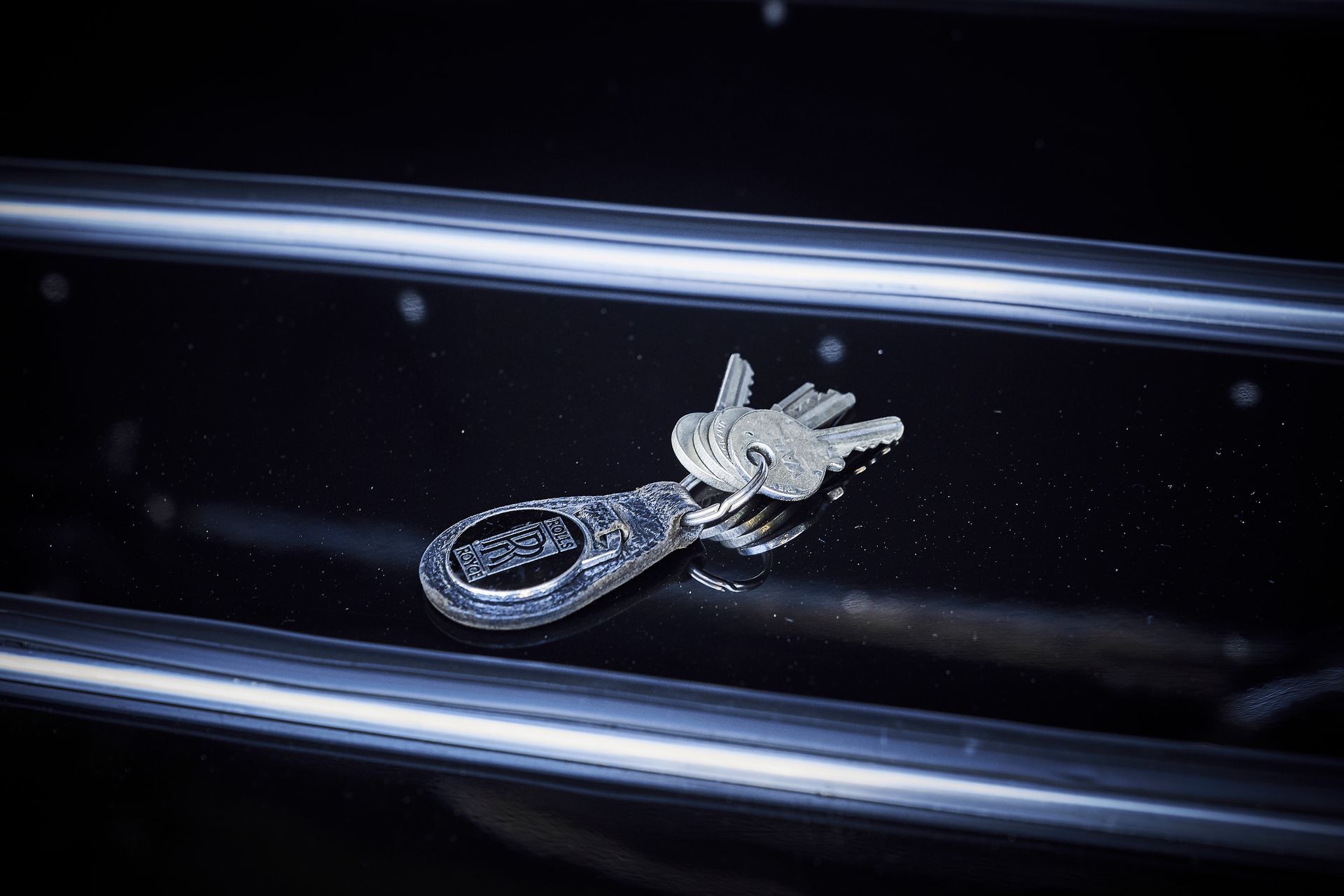 A pair of keys are laying on a black surface.