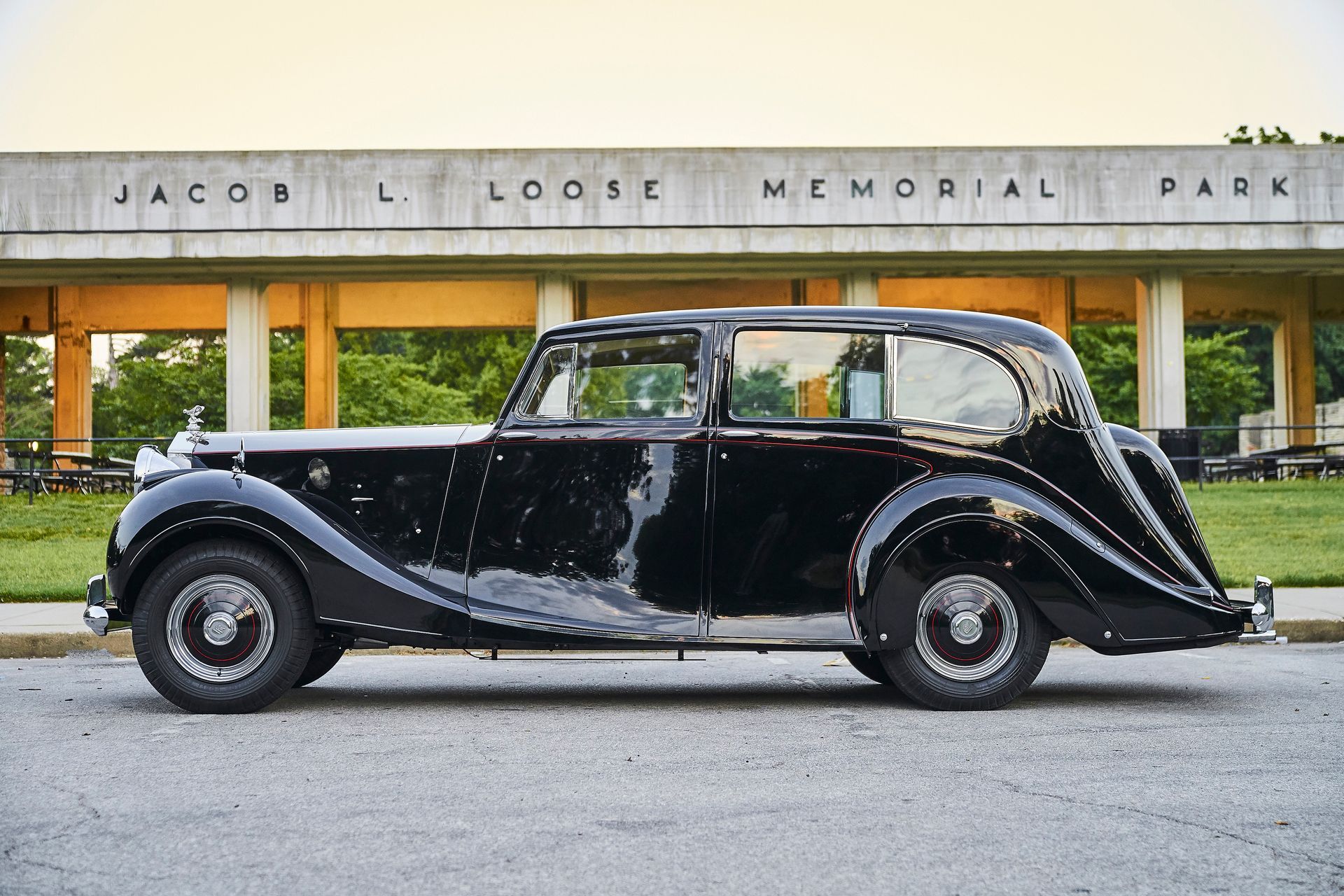 A black car is parked in front of a building that says loose memorial park.