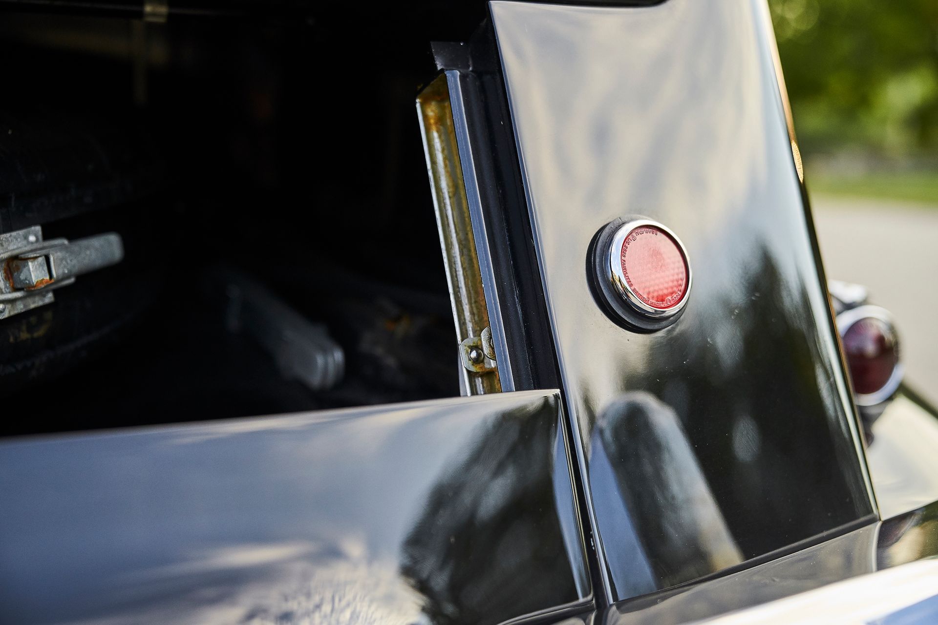 A close up of a black car with a red light on the side.