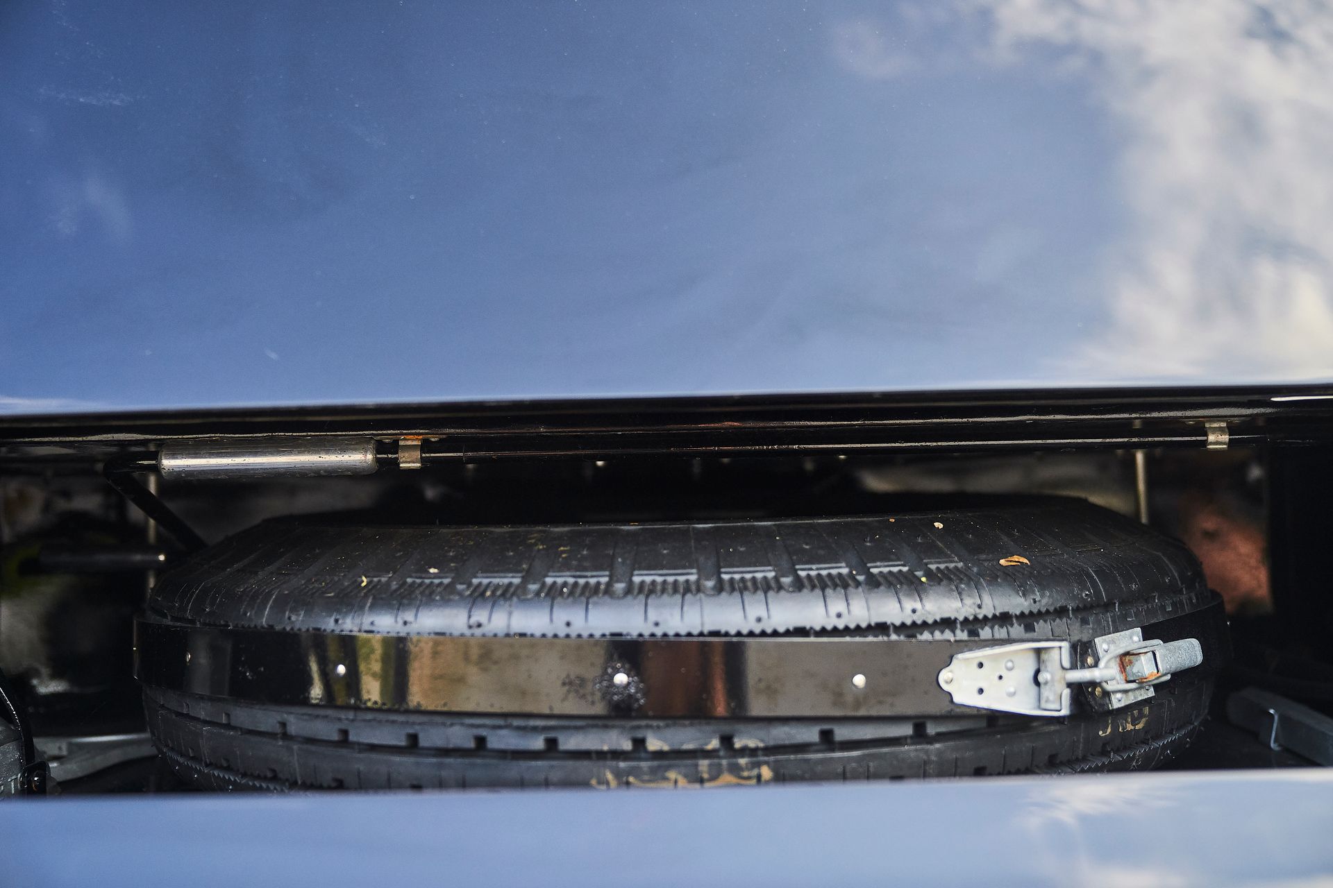 A person is looking under the hood of a car.