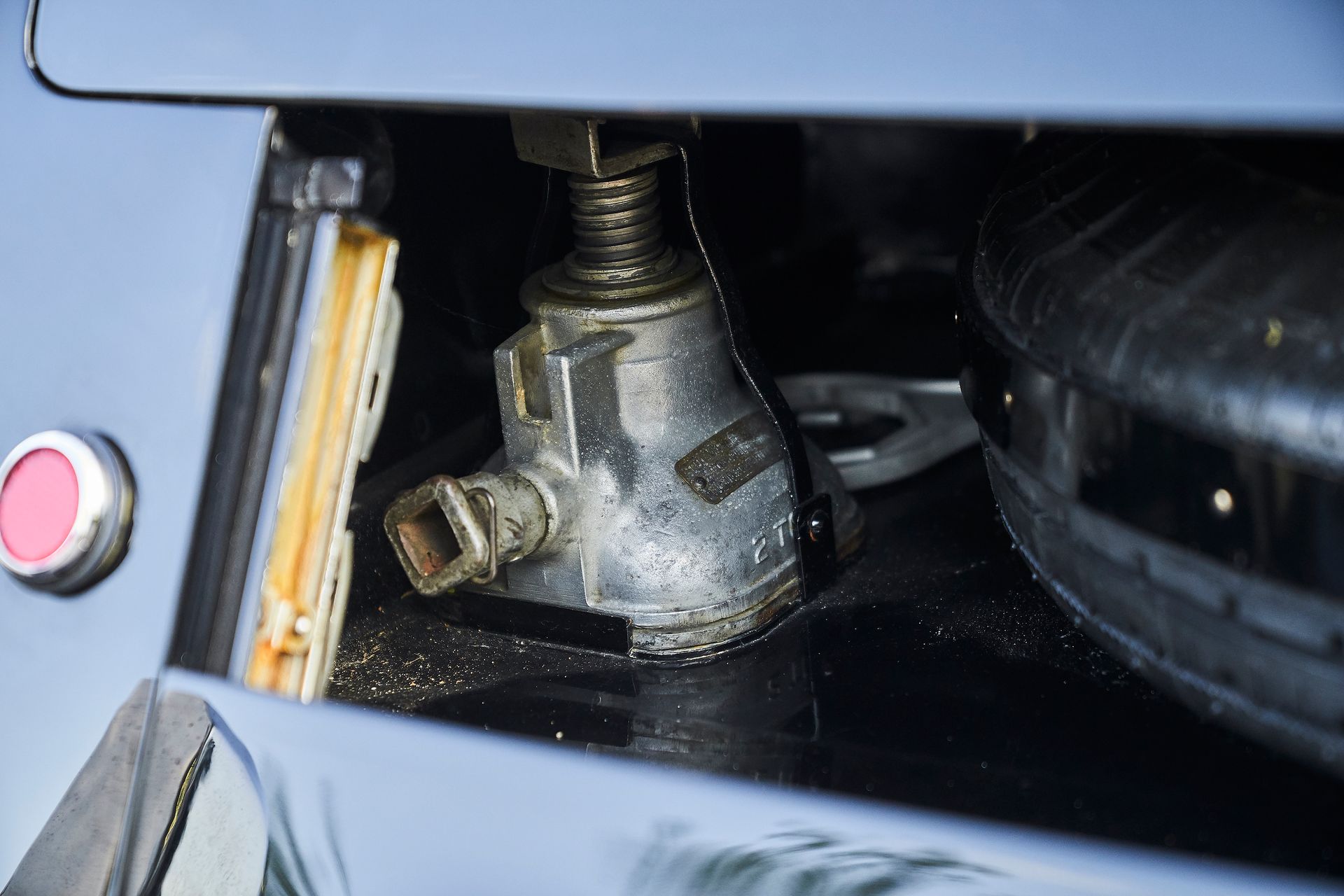 A jack is sitting under the hood of a car.