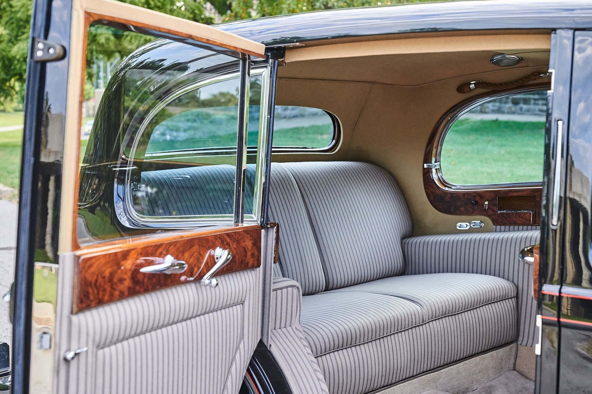 The inside of an old car with a couch in the back seat.