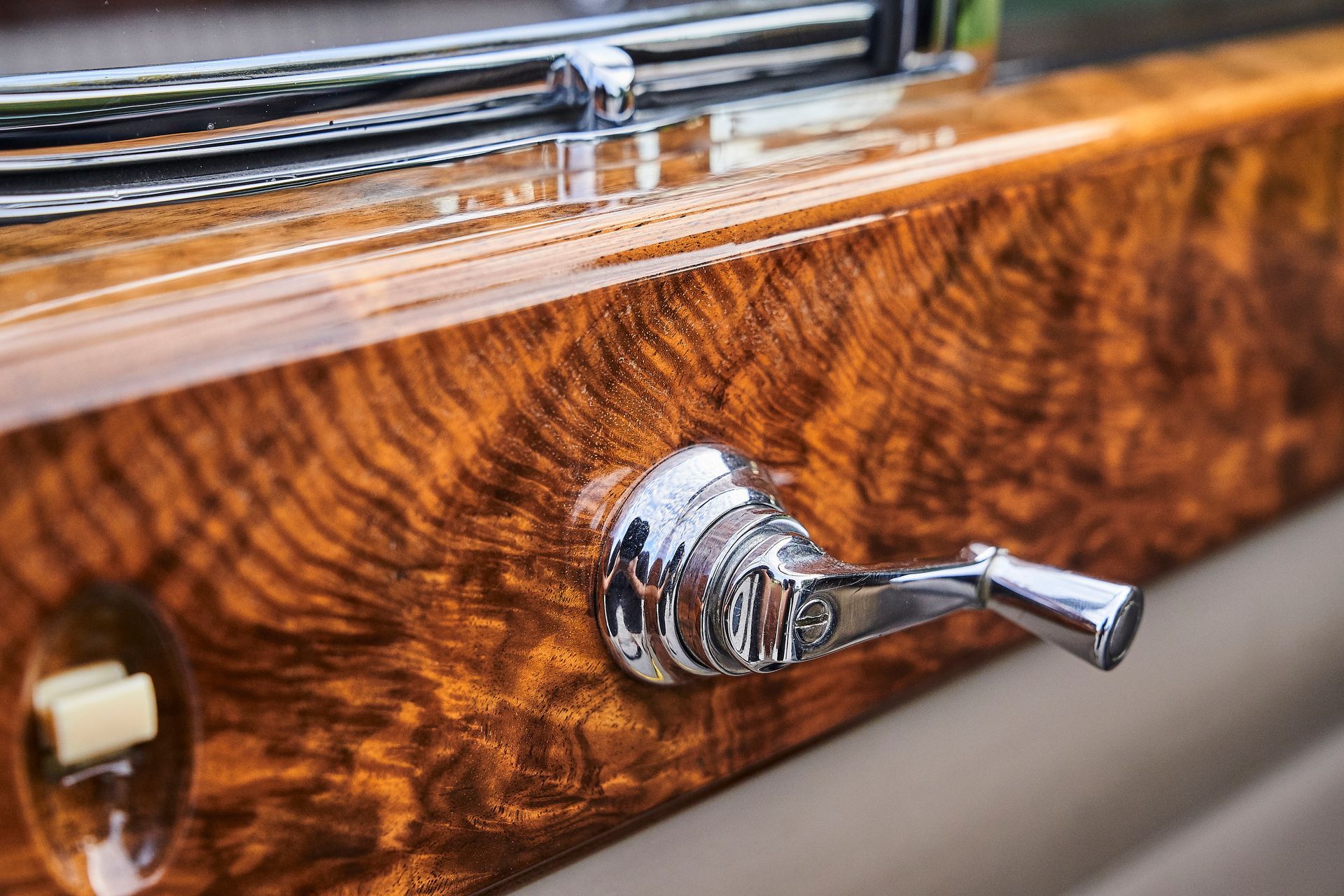 A close up of a wooden car door with a chrome handle.