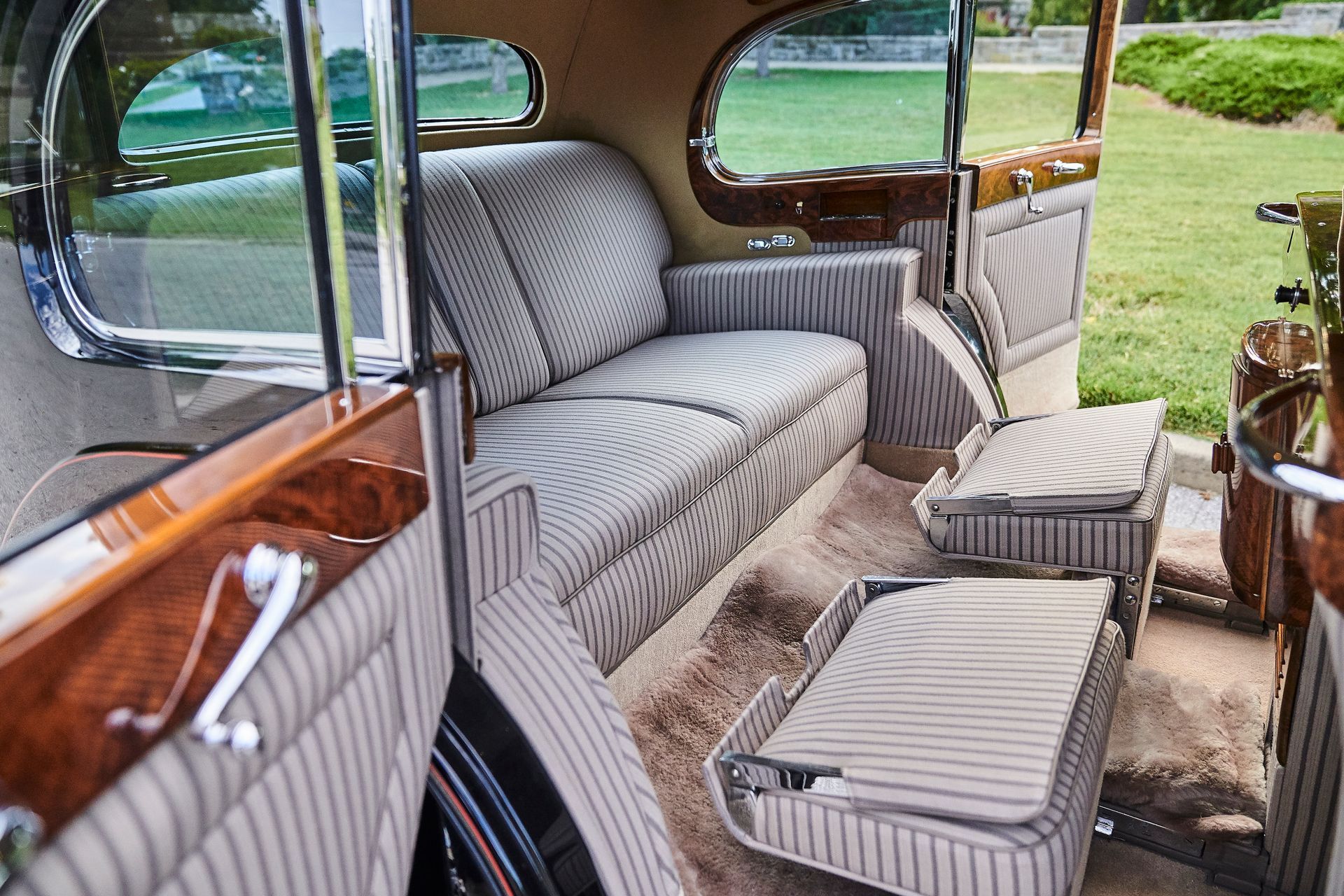 The inside of an old car with a couch and ottoman.