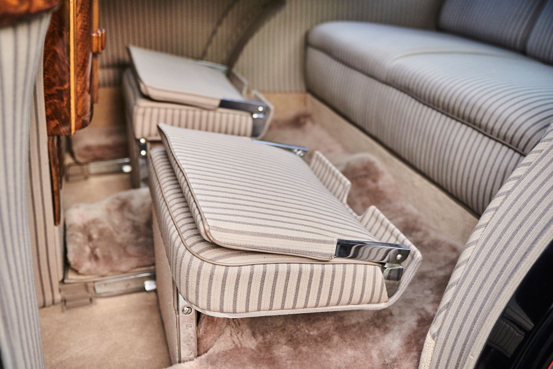 The back seat of a car with a couch and a stool.