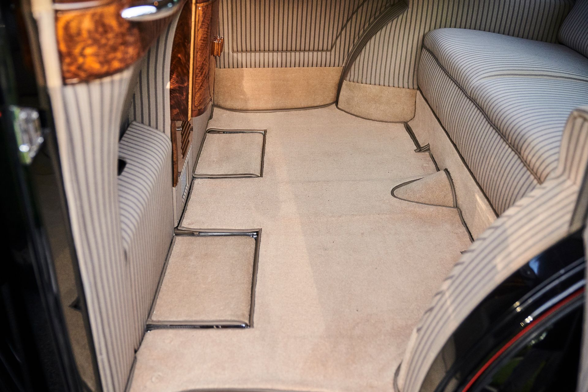 The back seat of a car with a carpeted floor.