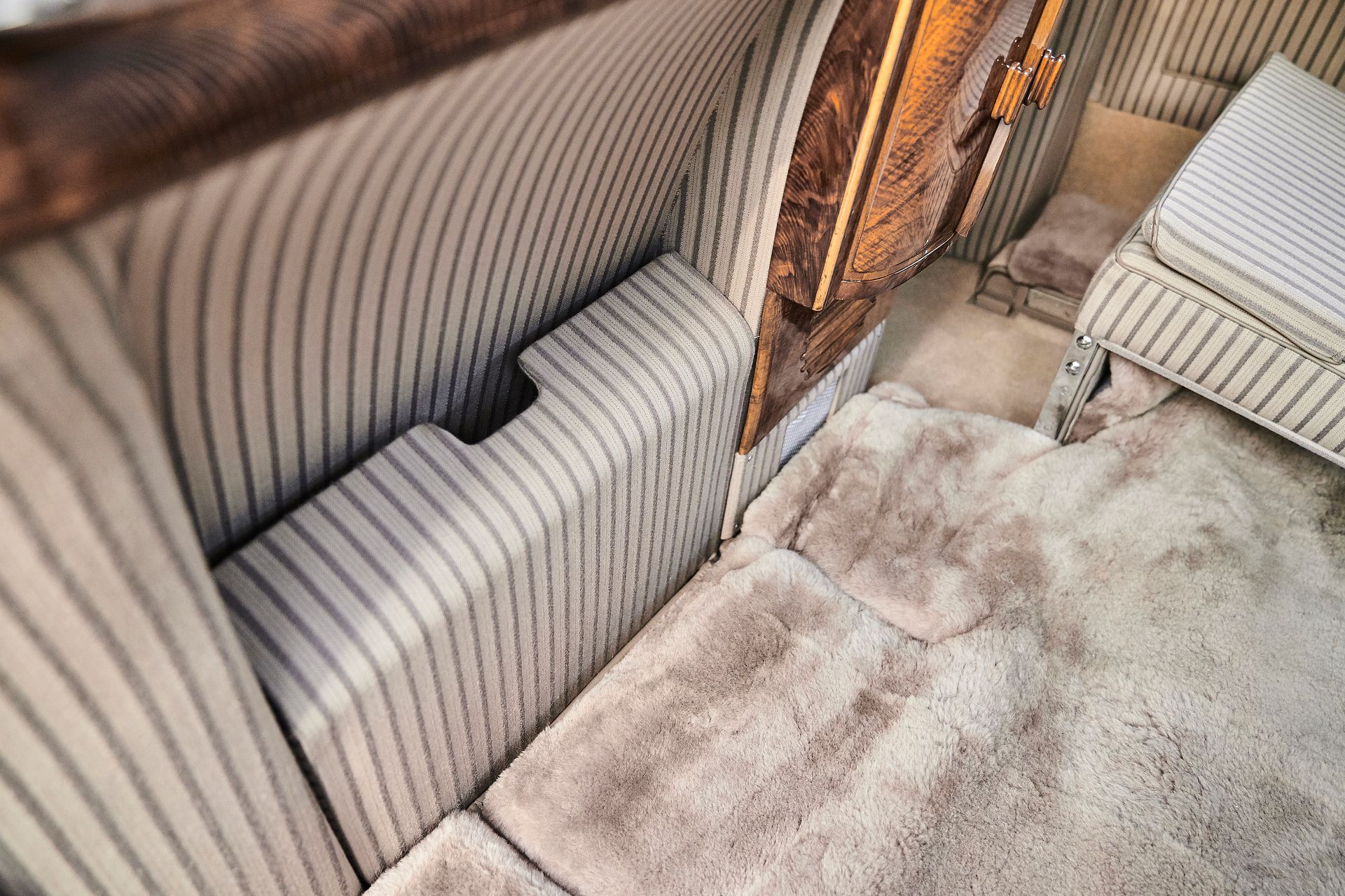 A room with a striped couch and a rug on the floor.