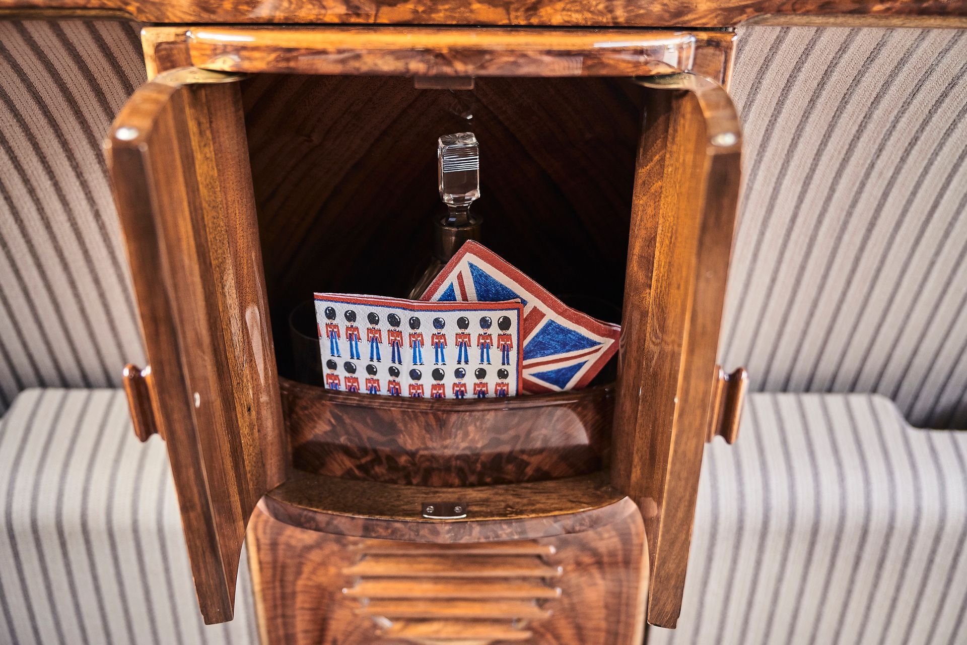 A wooden cabinet with a glass and playing cards in it.