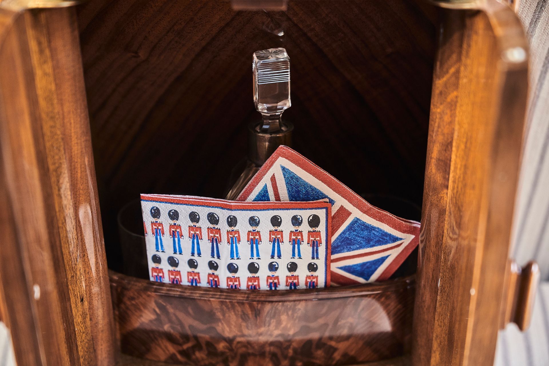 A wooden box with a decanter and napkins with british soldiers on them