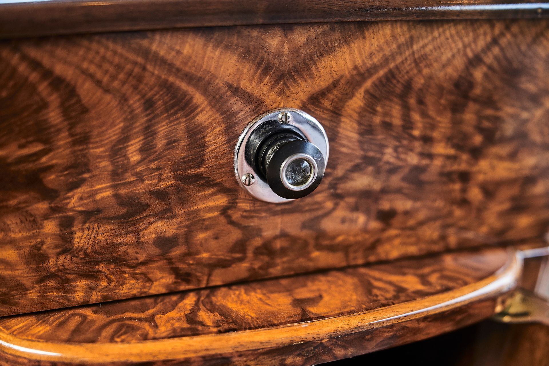 A close up of a wooden drawer with a metal knob on it.