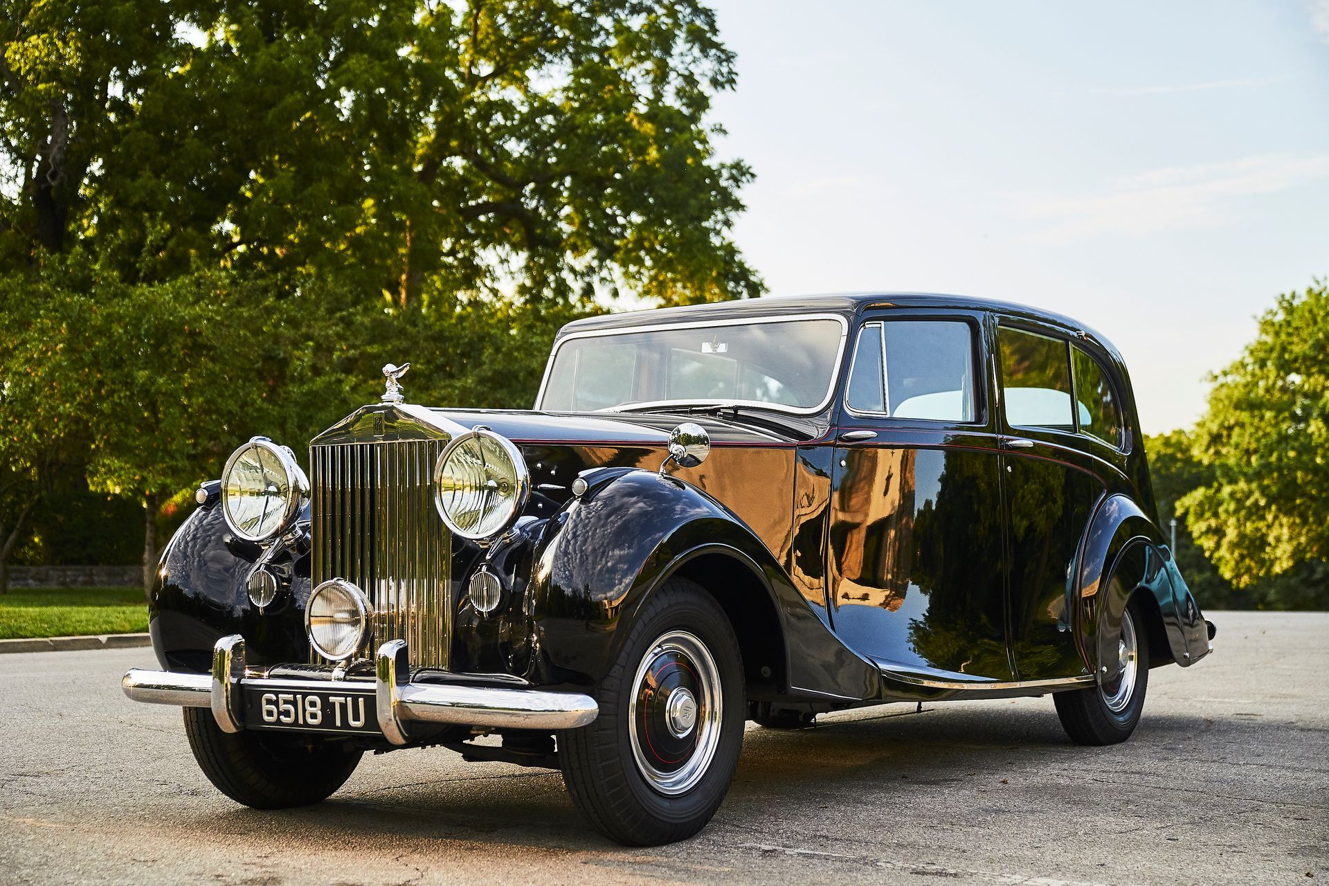 A black rolls royce car is parked in a parking lot.