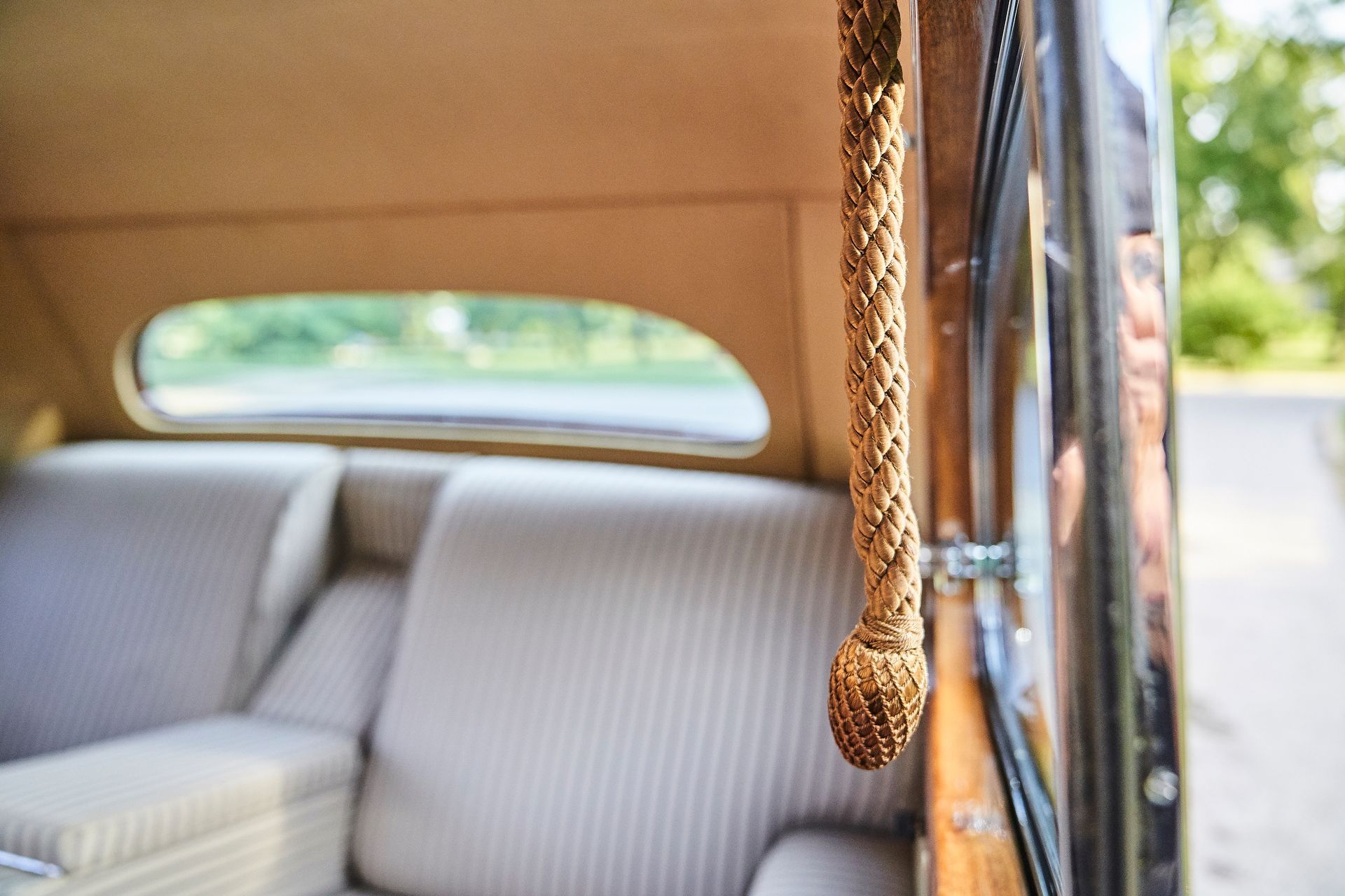 A close up of the back seat of a car with a wooden handle.