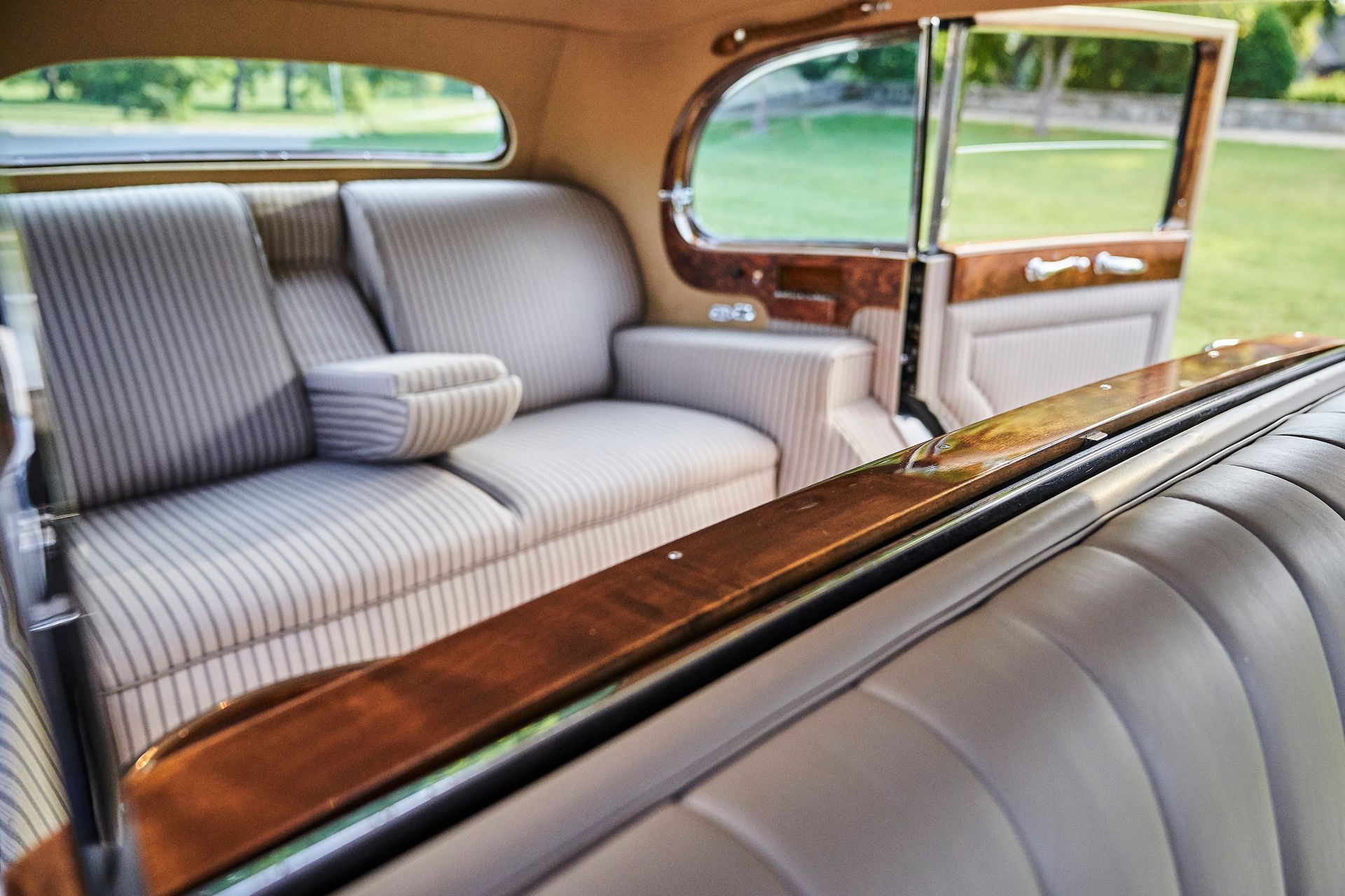 The back seat of an old car has a couch and a wooden table.