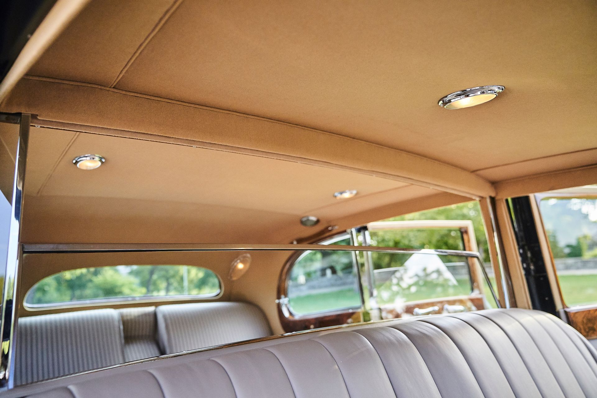 The back seat of a car with a tan ceiling