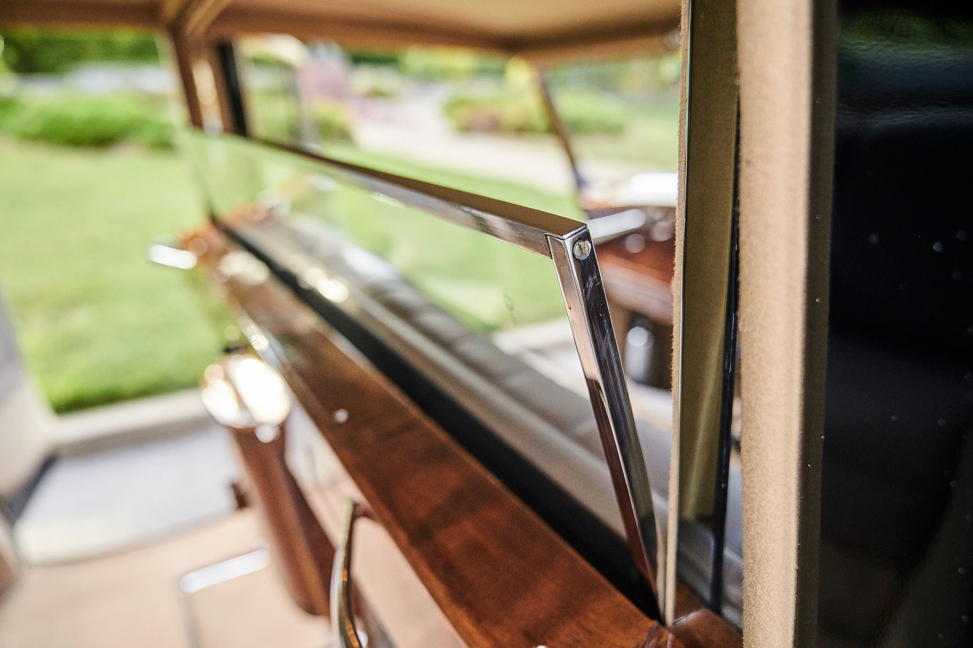 A close up of a car window with a wooden trim.