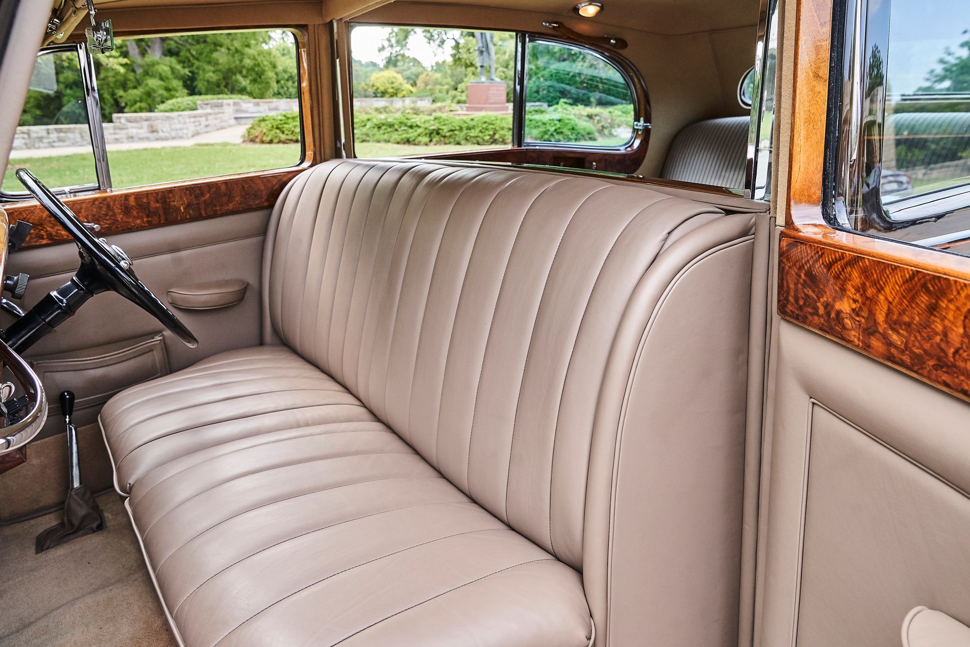 The back seat of an old car with a steering wheel
