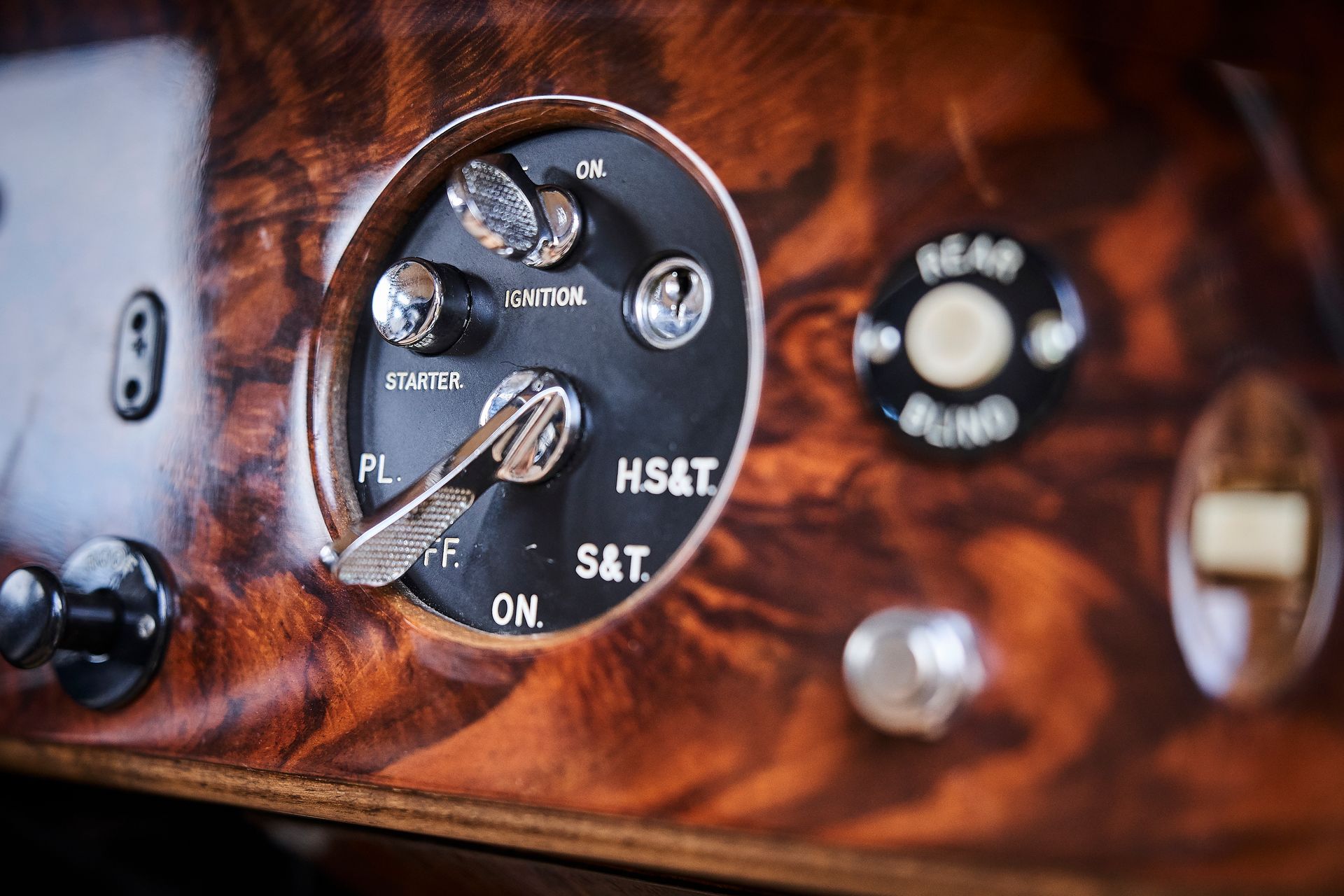 A close up of a wooden dashboard with a clock and buttons on it.