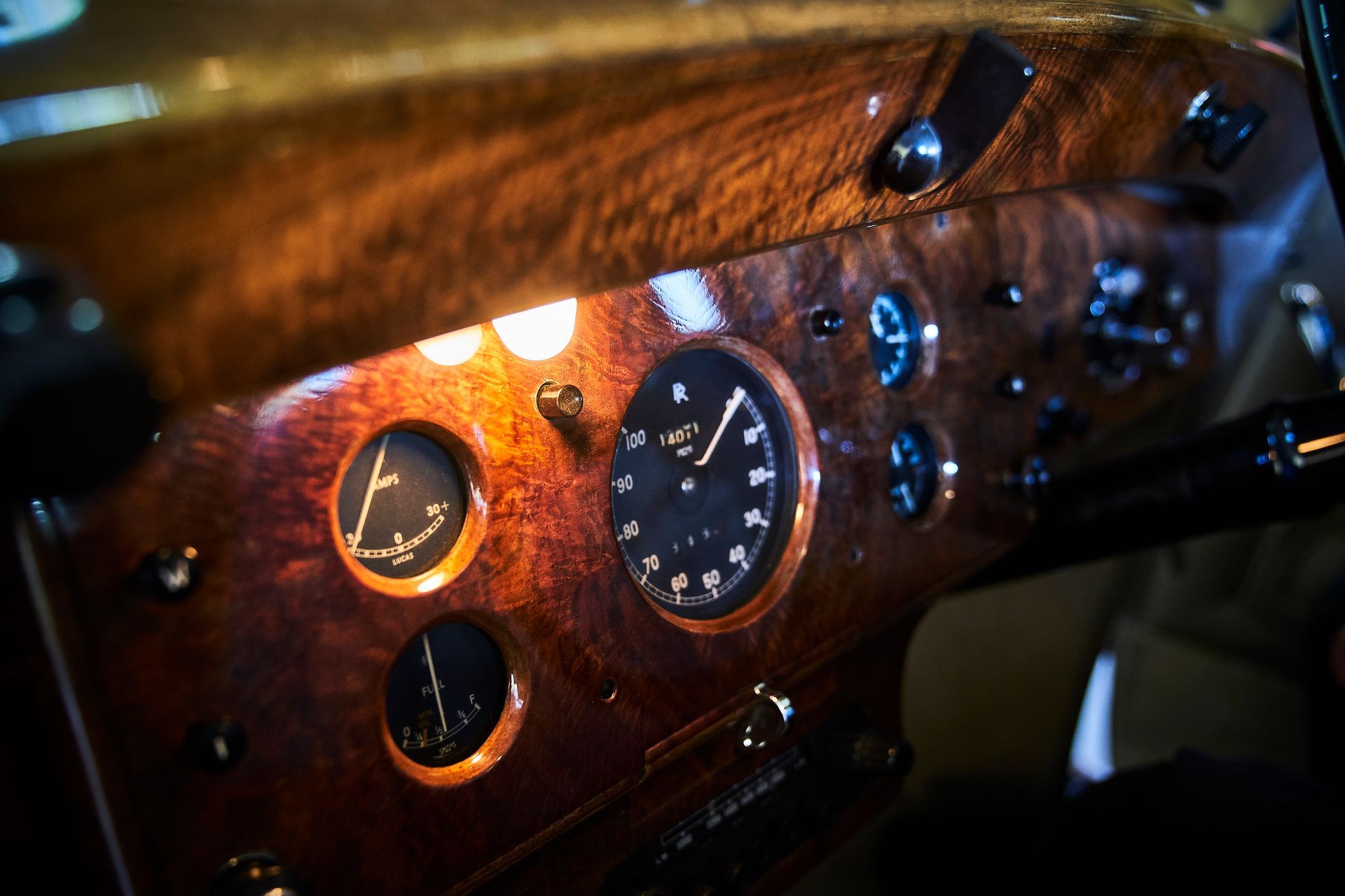A close up of a wooden dashboard of a car with a clock on it.