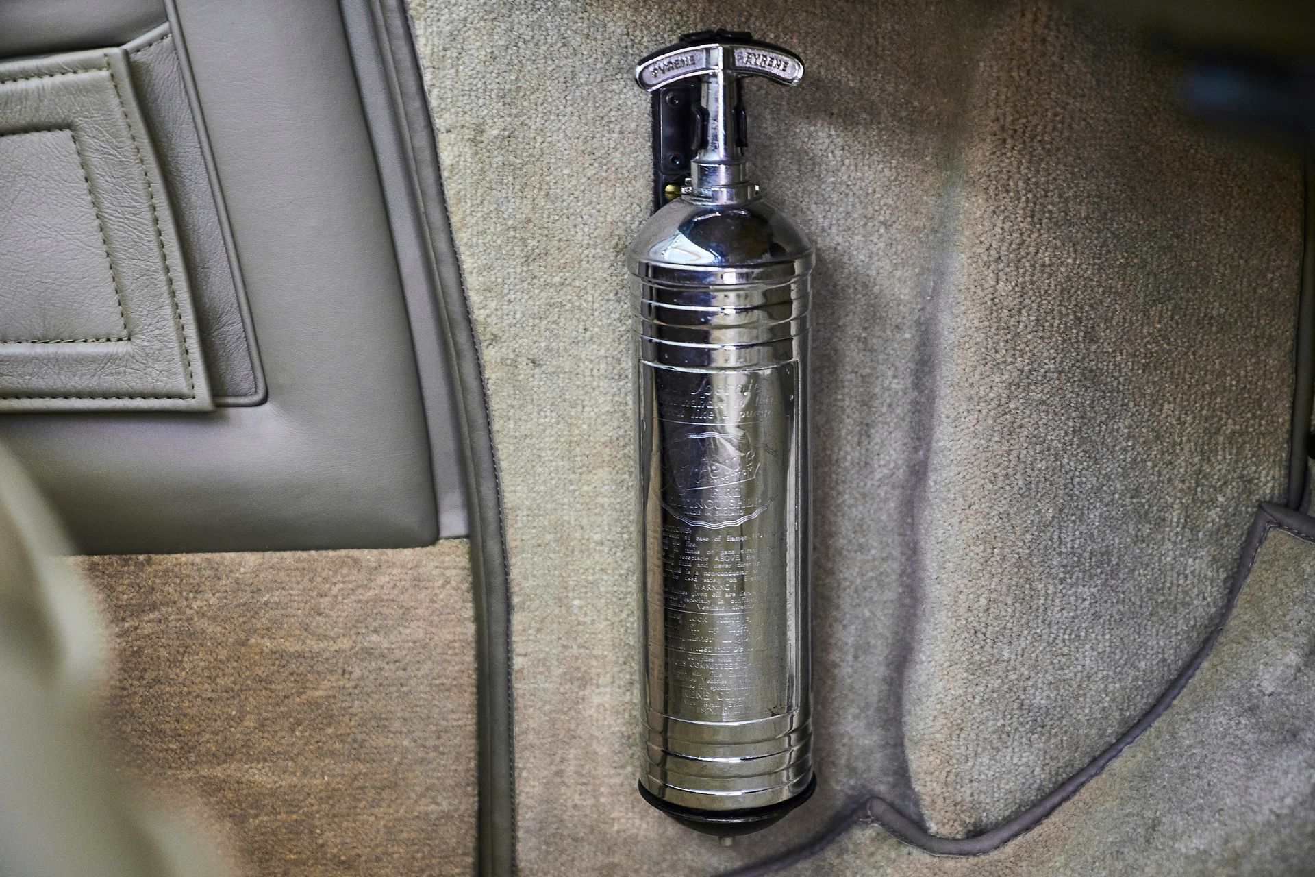 A fire extinguisher is sitting on the floor of a car.