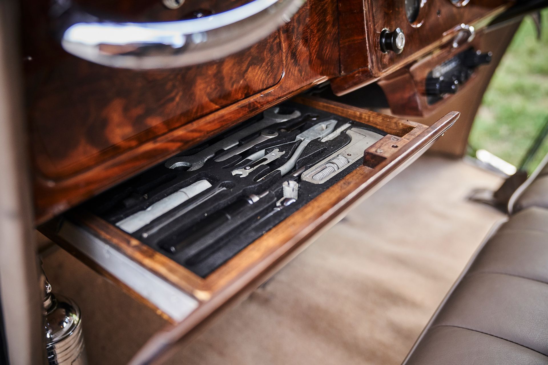 A wooden drawer in a car with a tray of silverware in it.