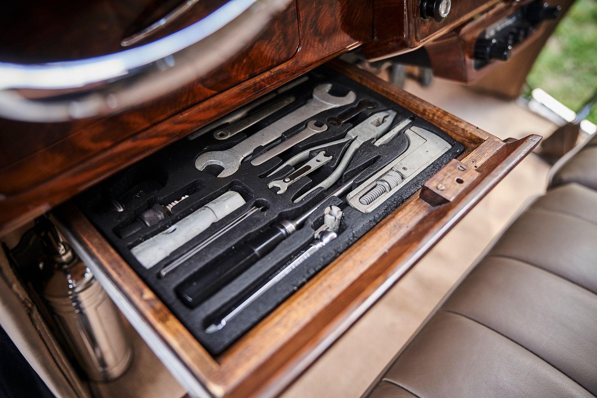A wooden drawer filled with tools in a car.