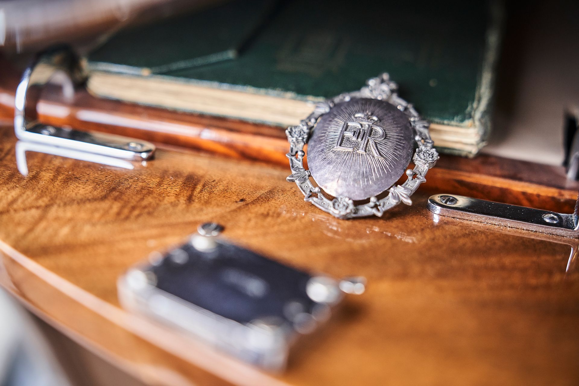 A wooden table with a book and a pendant on it.