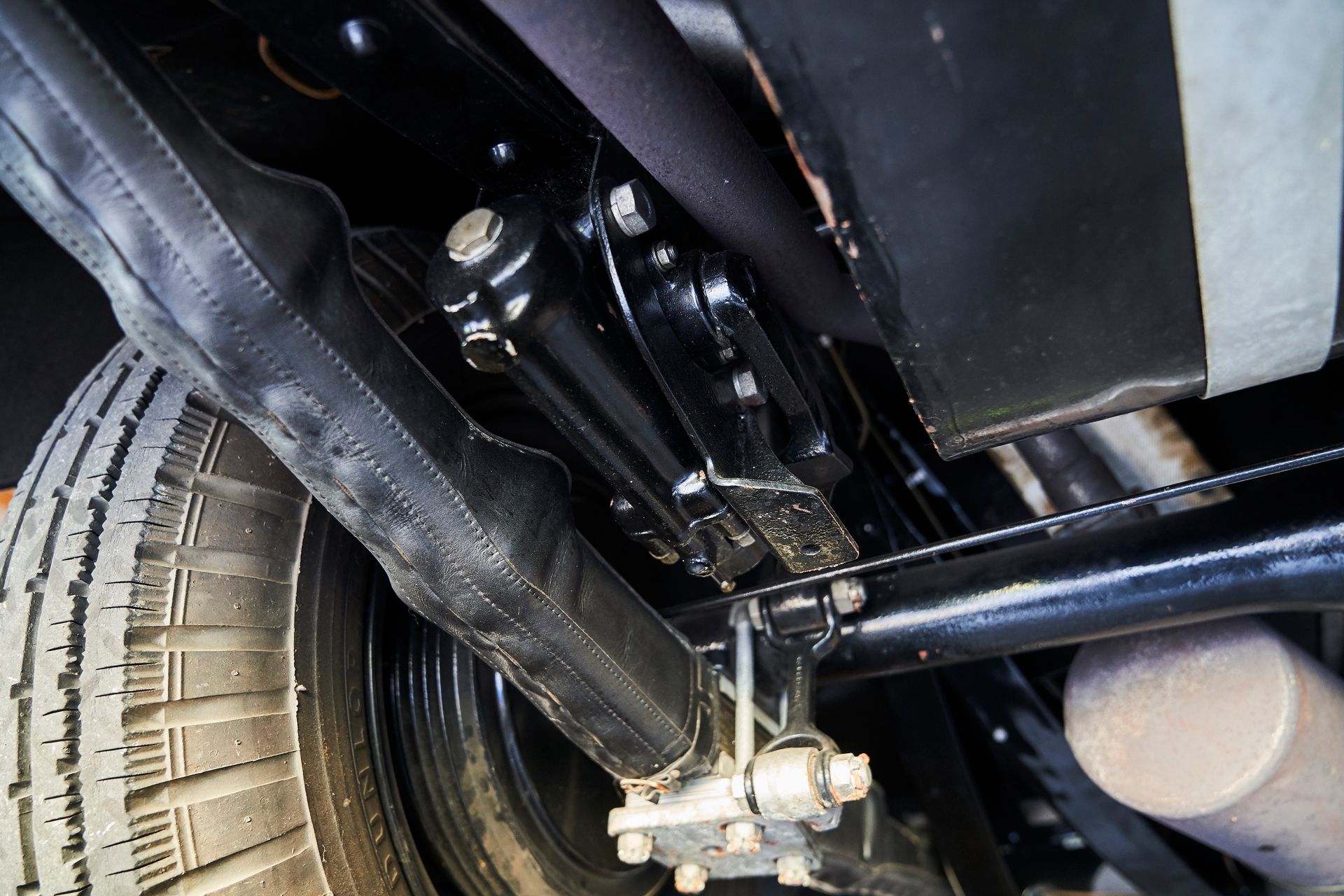 A close up of the underside of a car with a tire and exhaust pipe.