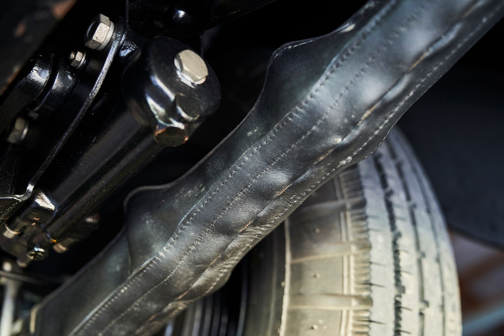 A close up of the underside of a car with a tire in the background.
