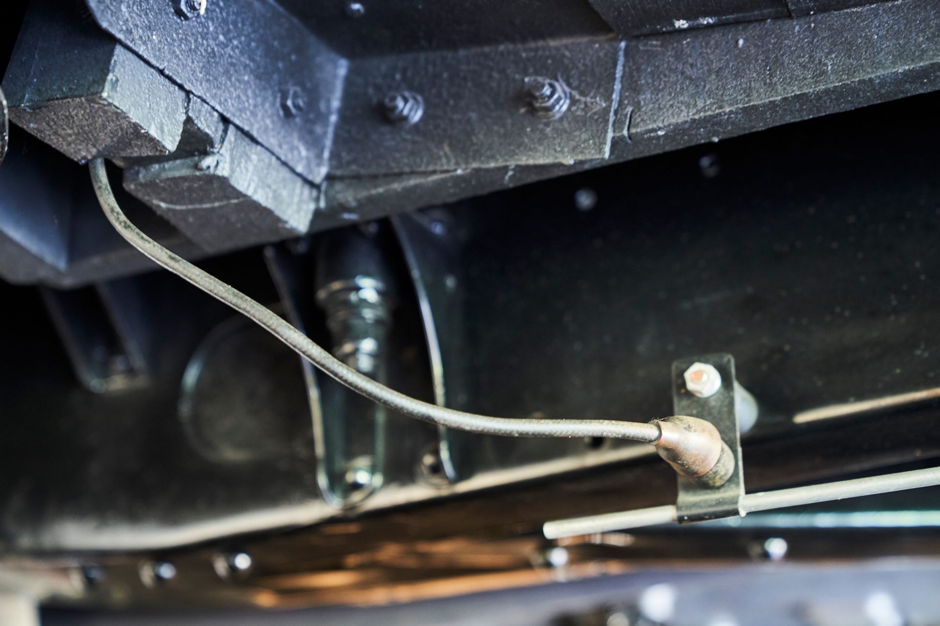 A close up of the underside of a car with a hose attached to it.