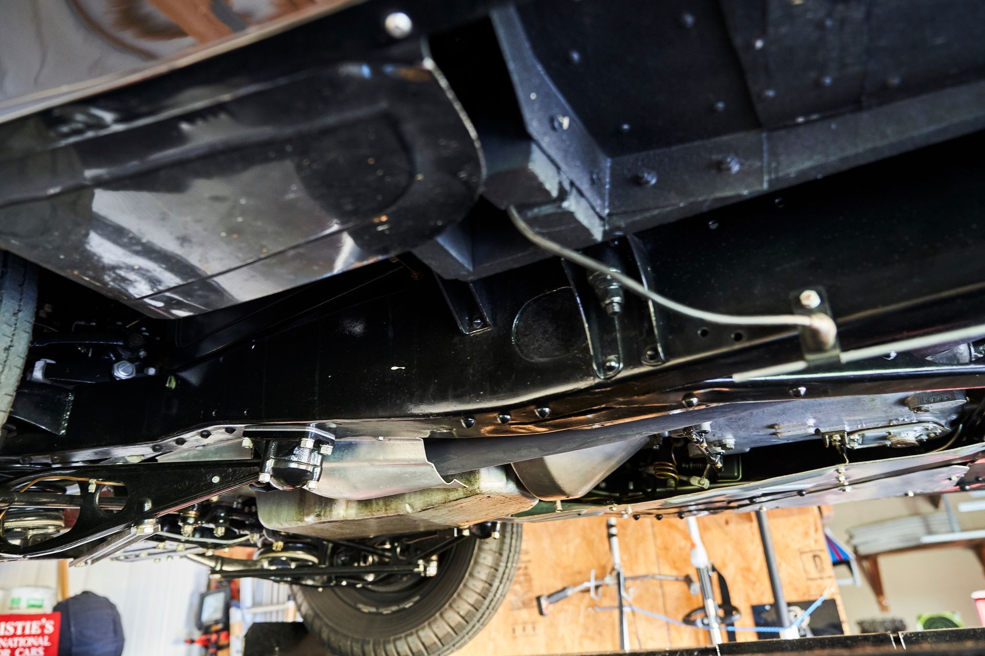 The underside of a car is shown in a garage.