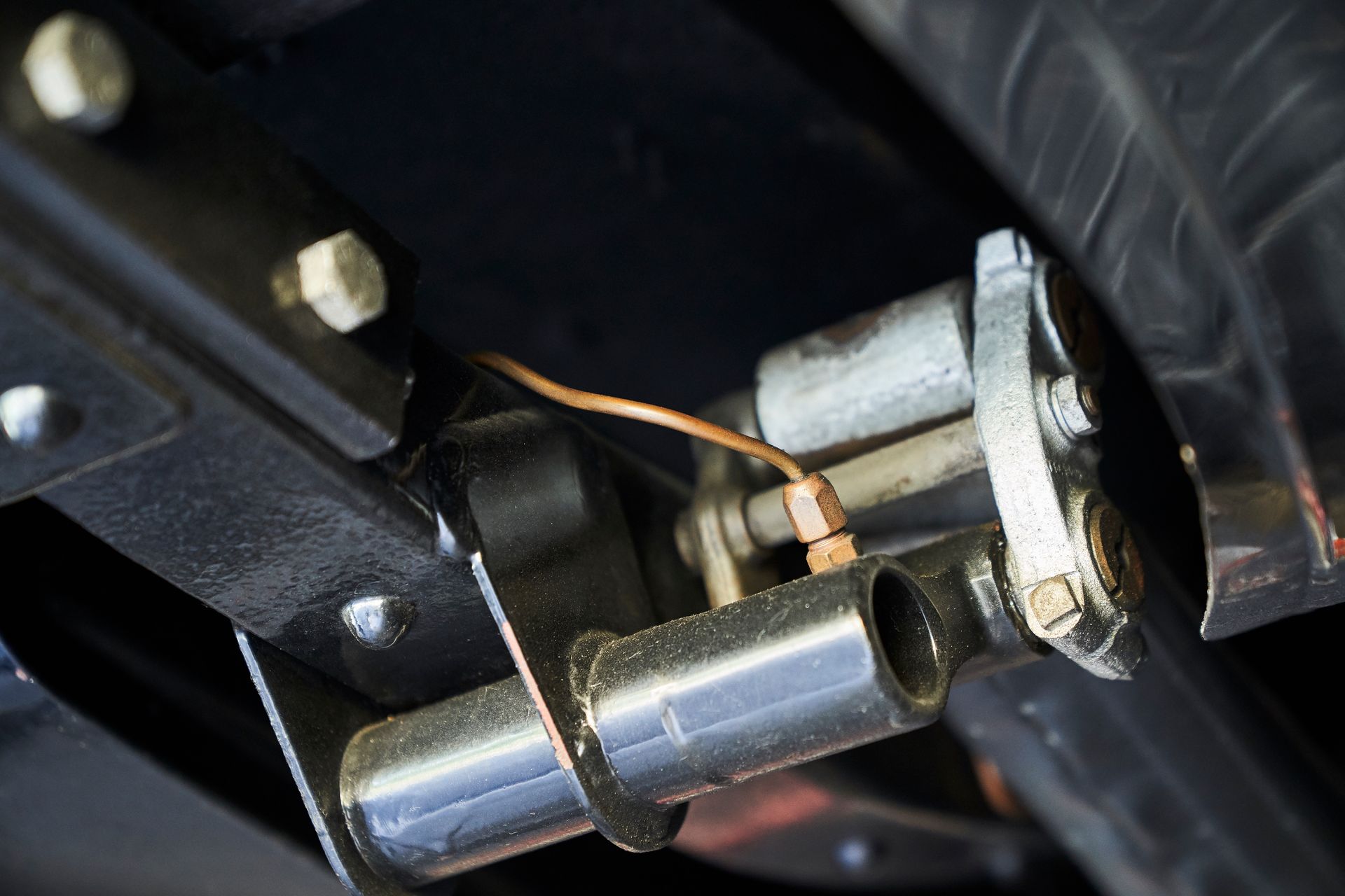 A close up of a metal pipe with a copper hose attached to it.