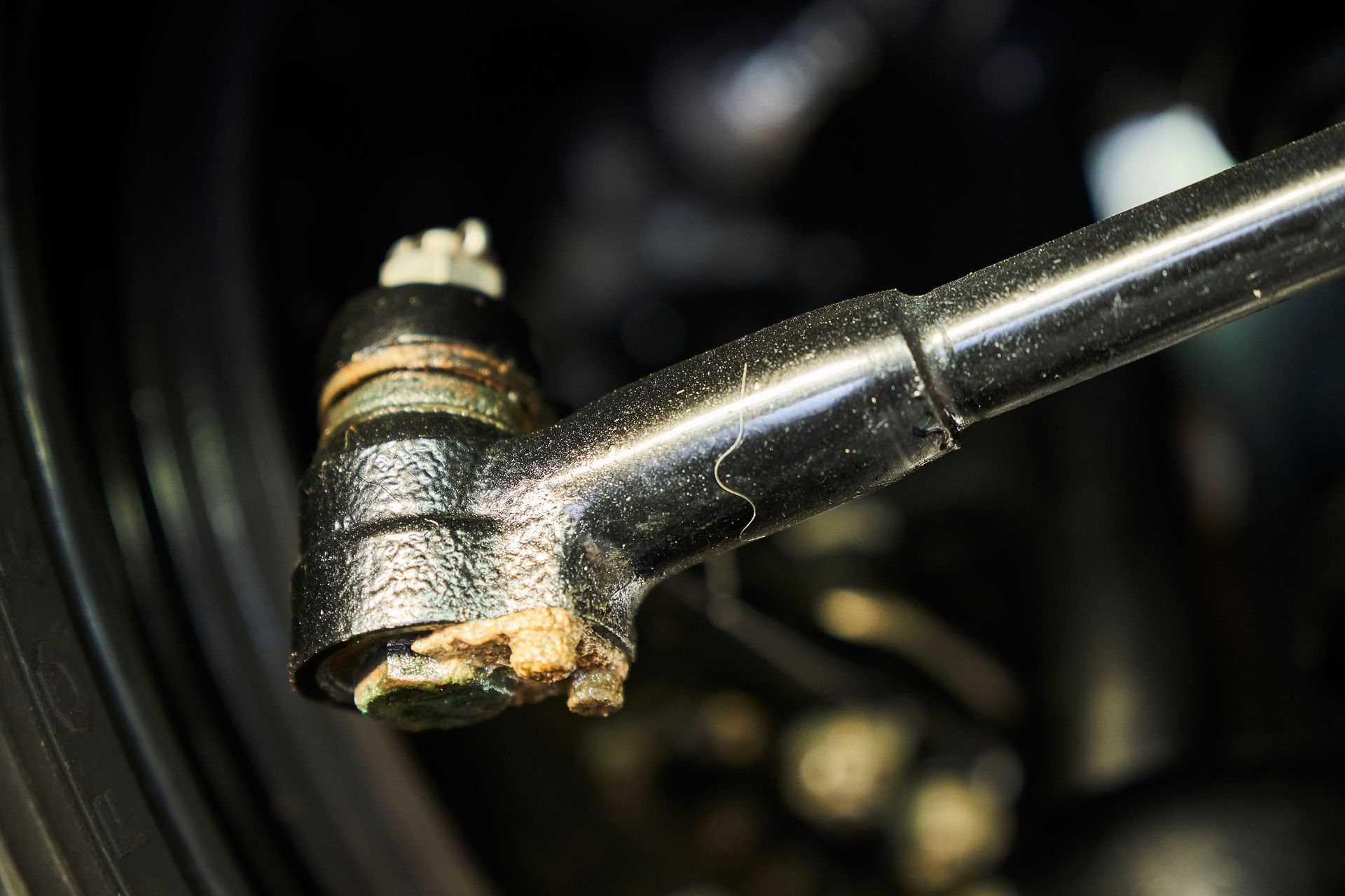 A close up of a tie rod on a car wheel.