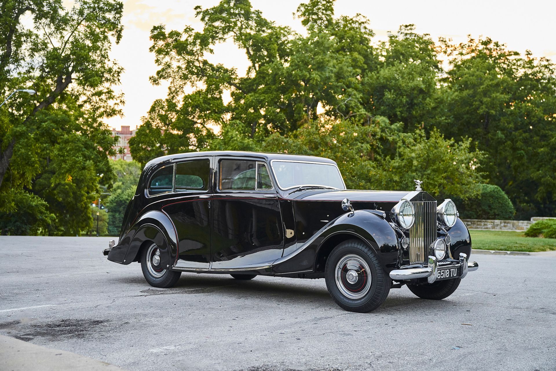 An old black car is parked on the side of the road.