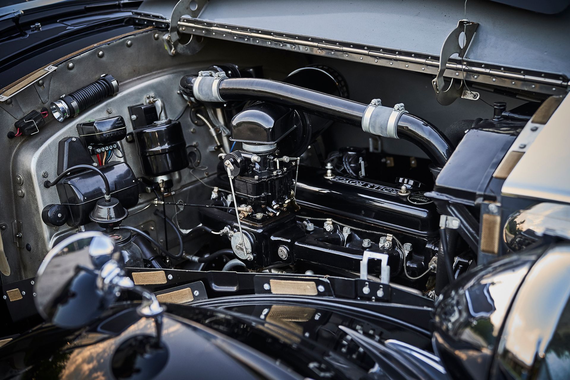 A close up of a black car engine with the hood open