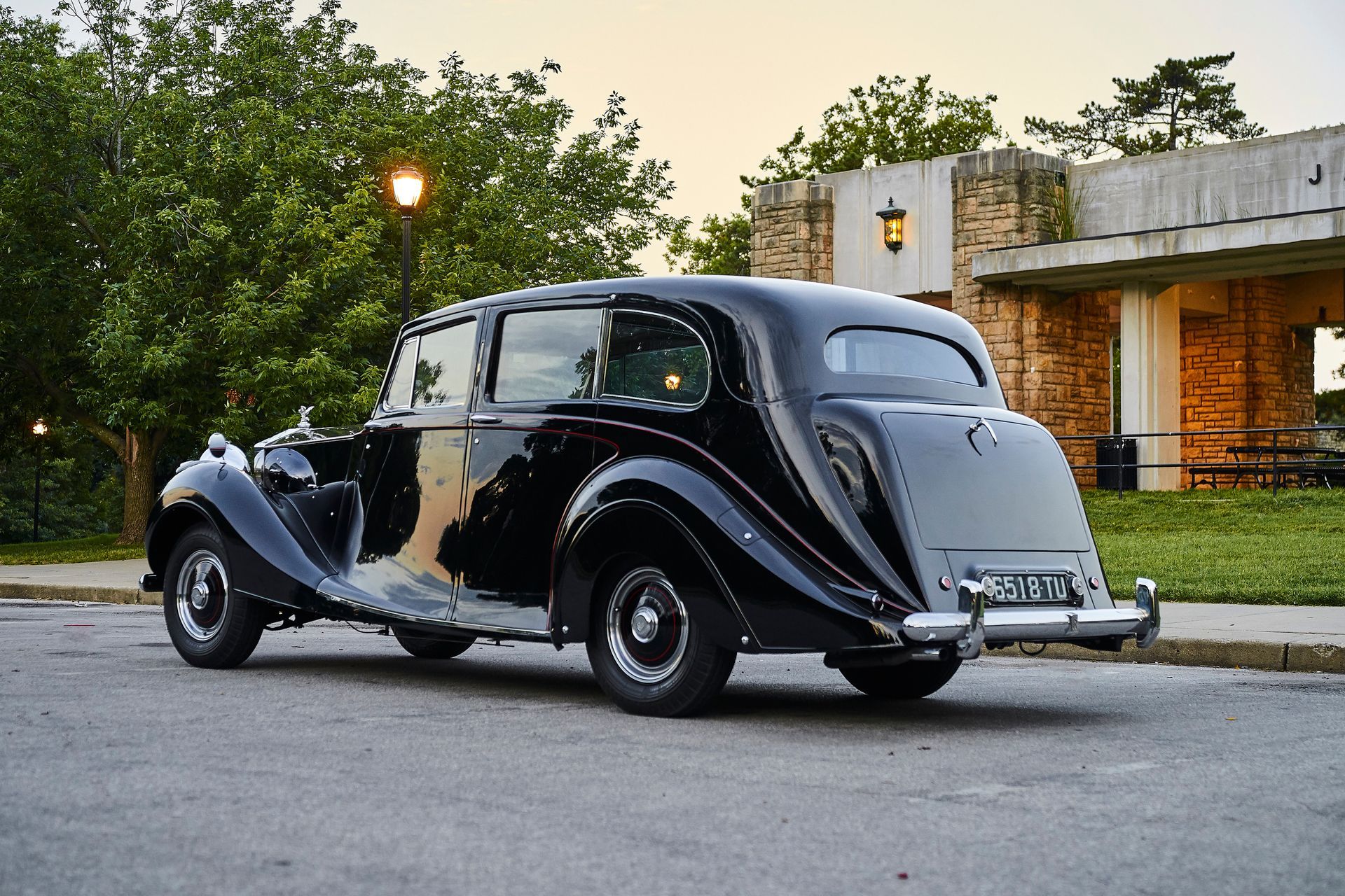 A black car is parked on the side of the road in front of a building.